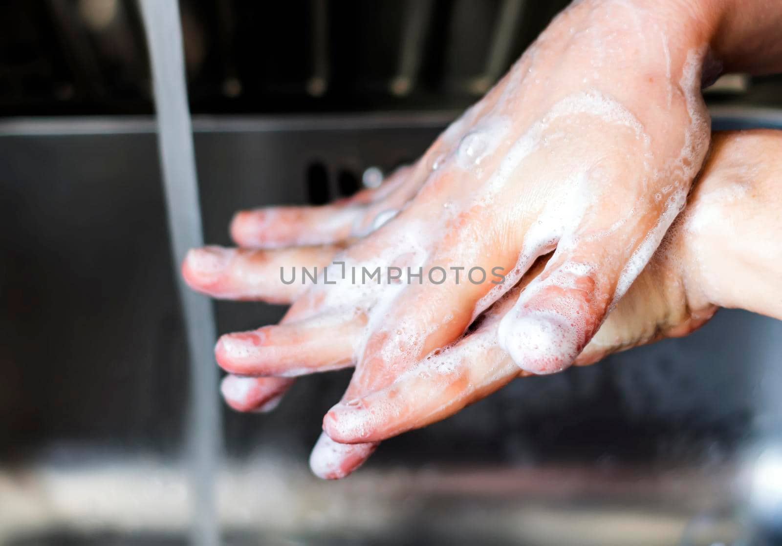 young caucasian woman washing her hands with soap. Right hand over of the left hand. Keeping hands clean. Personal care