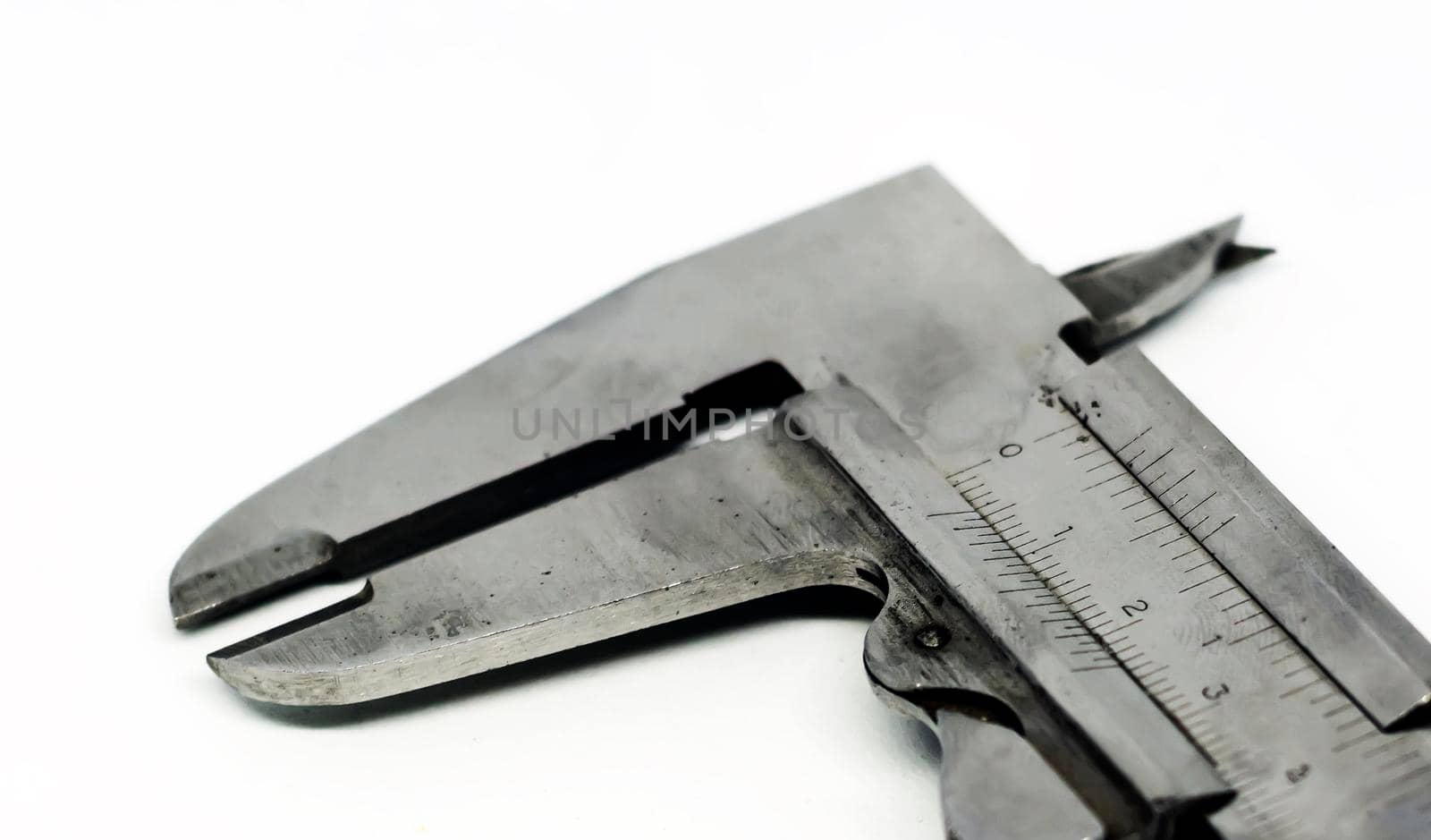 Detail view of a metallic caliper used to measure the distance between two opposite sides of an object. Engineering and construction industry. Isolated on a white background