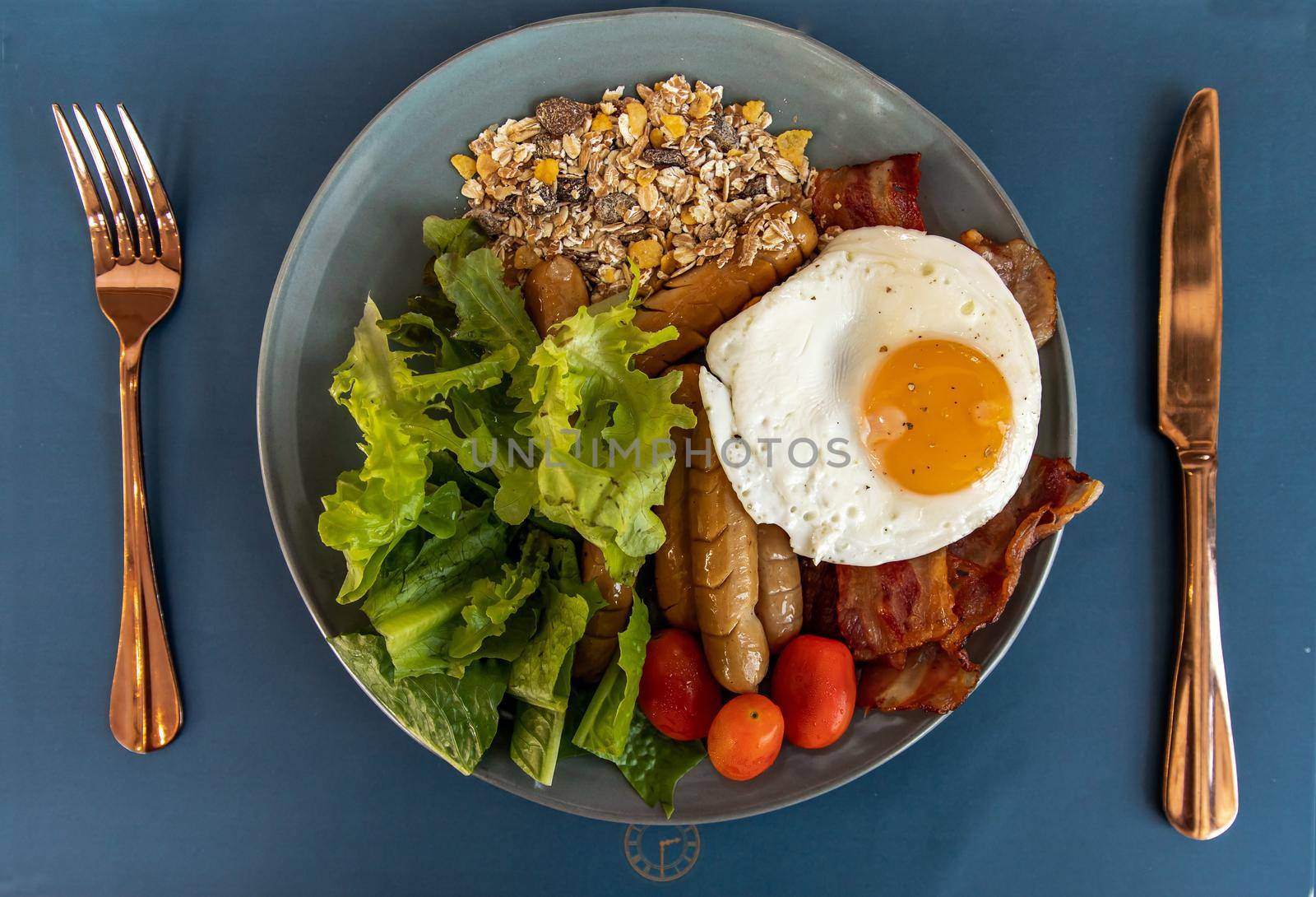 Continental breakfast with fried egg, fried sausages, vegetable on white plate. Selective focuse.