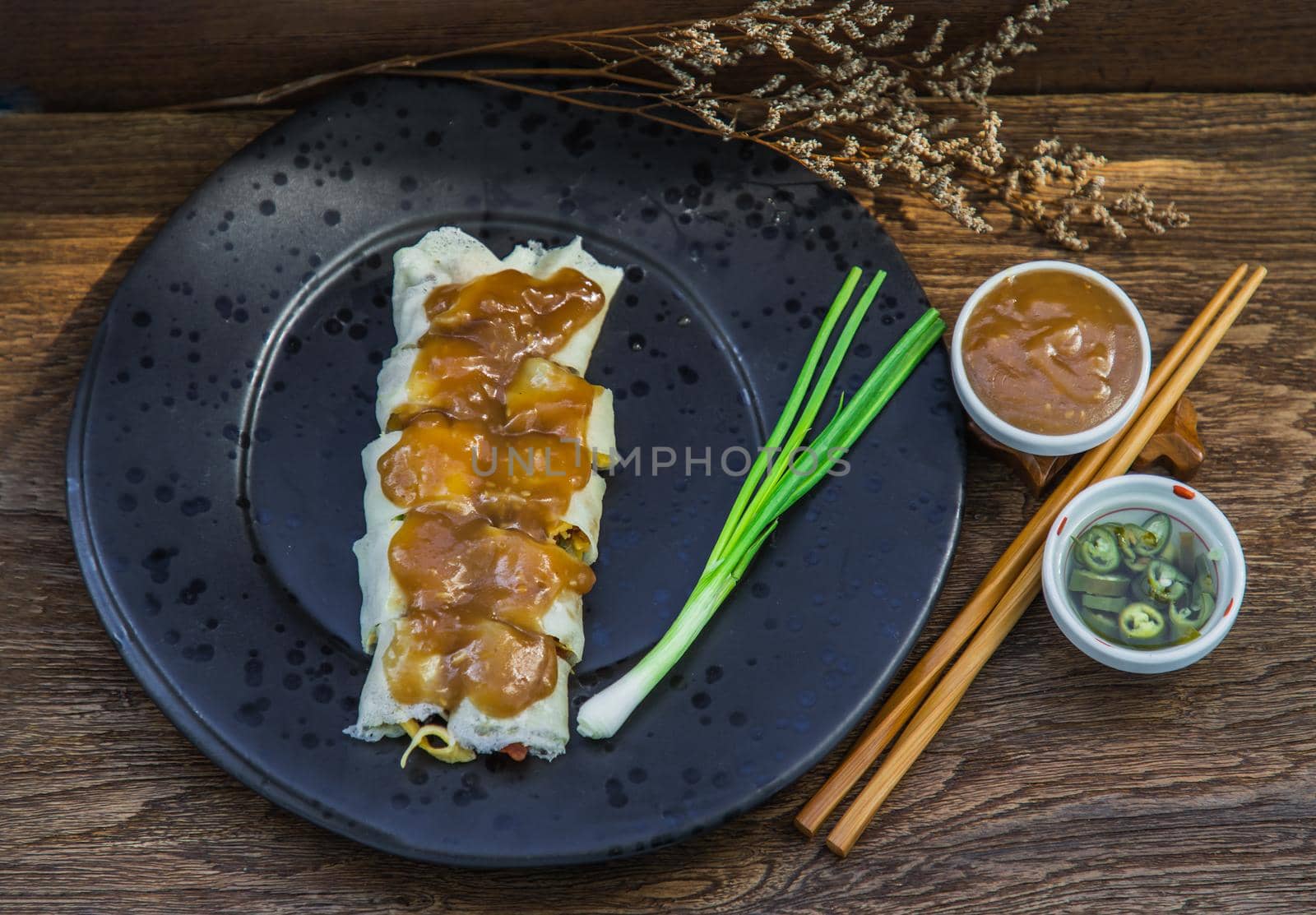 Thai fresh spring rolls Topped with Sweet sauce with Spring onions on black plate. Selective focus.