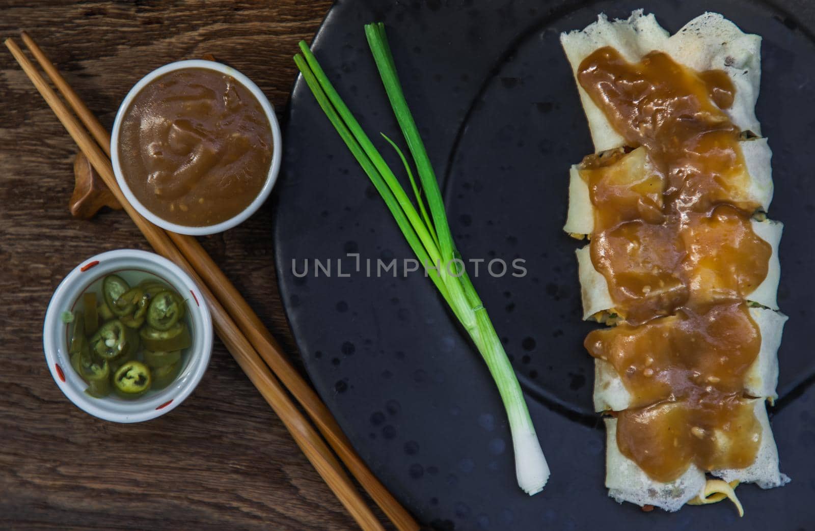 Thai fresh spring rolls Topped with Sweet sauce with Spring onions on black plate. Selective focus.
