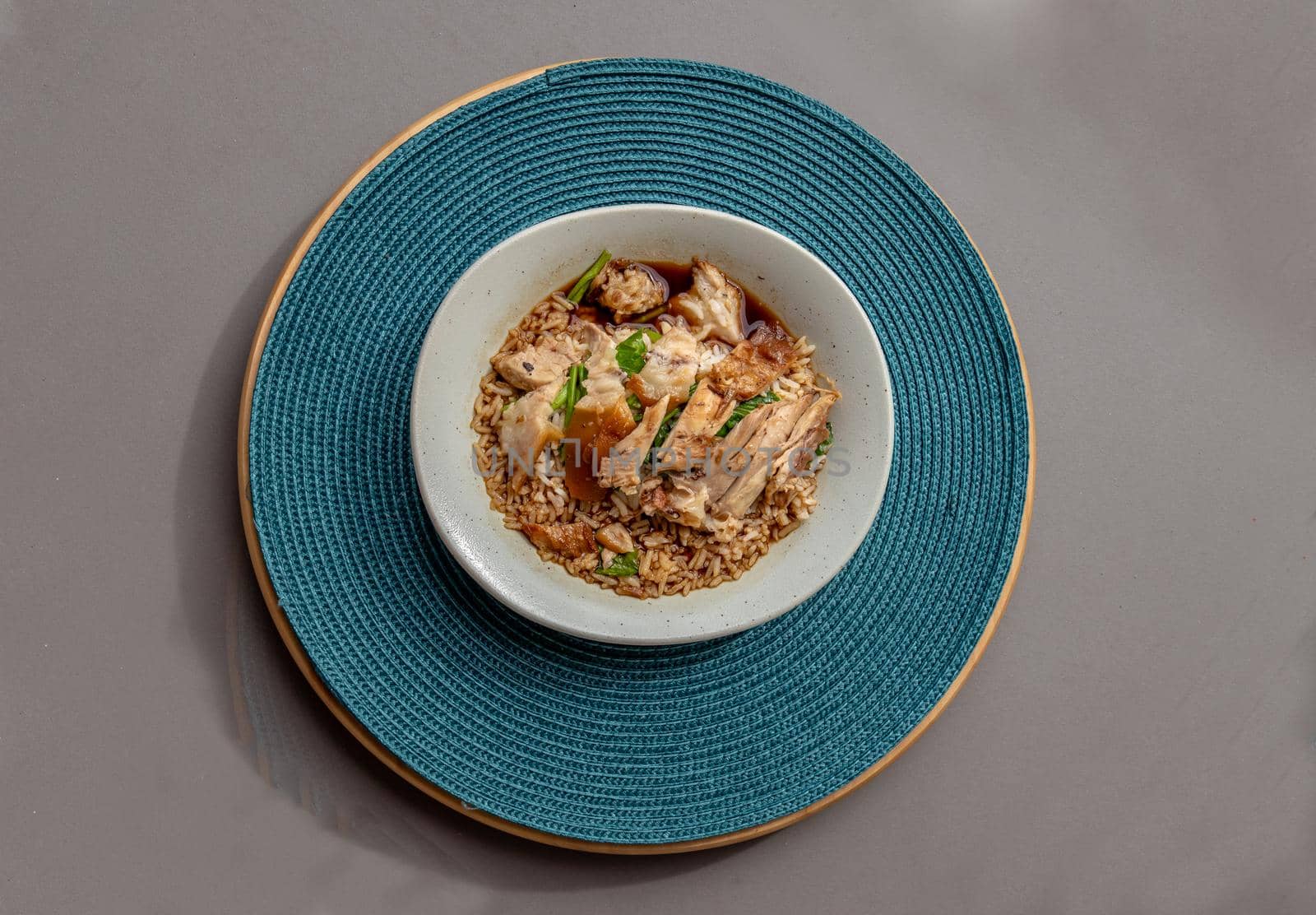 Thai stewed pork leg with rice on the blue round straw table mat. Top view, Selective focus.