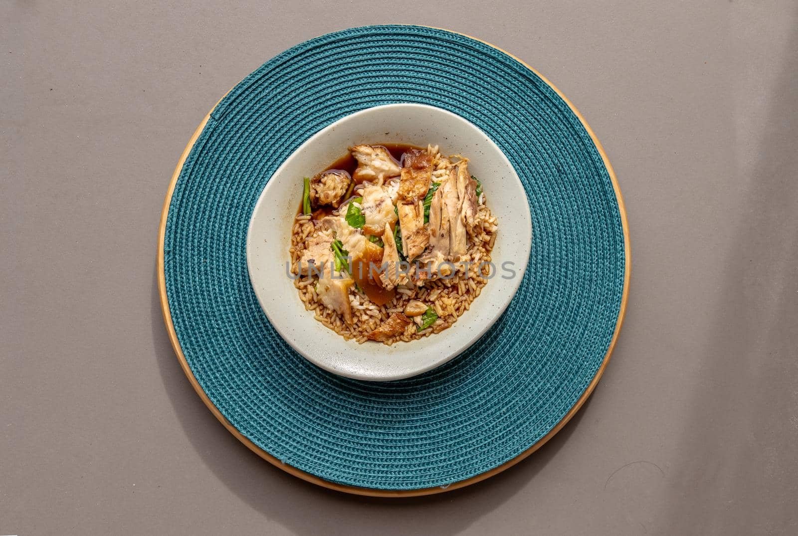 Thai stewed pork leg with rice on the blue round straw table mat. Top view, Selective focus.