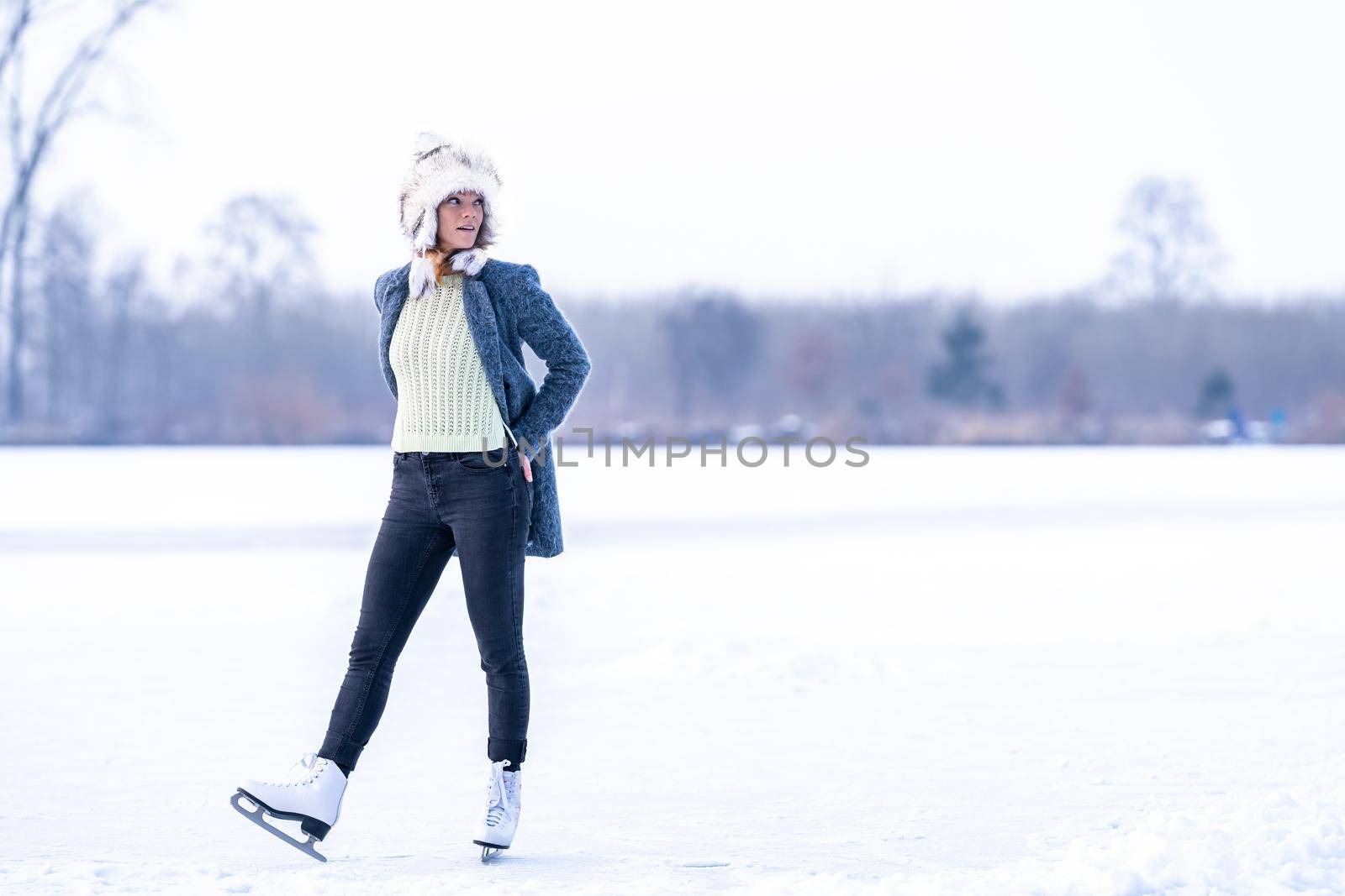 Gorgeous woman skating on frozen lake.