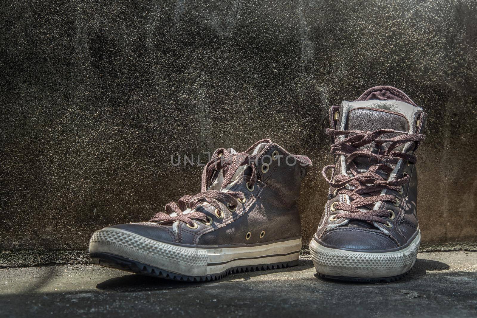 Brown Retro High Top Canvas Sneakers was placed on old cement floor. Vintage age-worn sneakers canvas shoes brown, Concept : Sometimes the long journey of life should rest. Copy space, Selective focus.