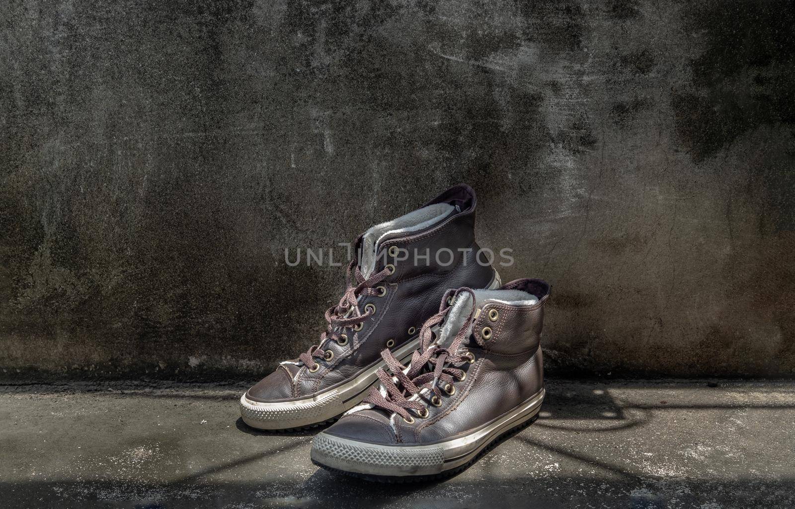 Brown Retro High Top Canvas Sneakers was placed on old cement floor. Vintage age-worn sneakers canvas shoes brown, Concept : Sometimes the long journey of life should rest. Copy space, Selective focus.