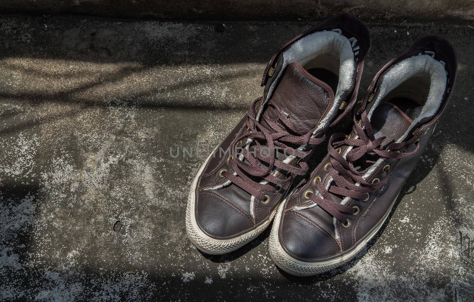 Brown Retro High Top Canvas Sneakers was placed on old cement floor. Vintage age-worn sneakers canvas shoes brown, Concept : Sometimes the long journey of life should rest. Copy space, Selective focus.