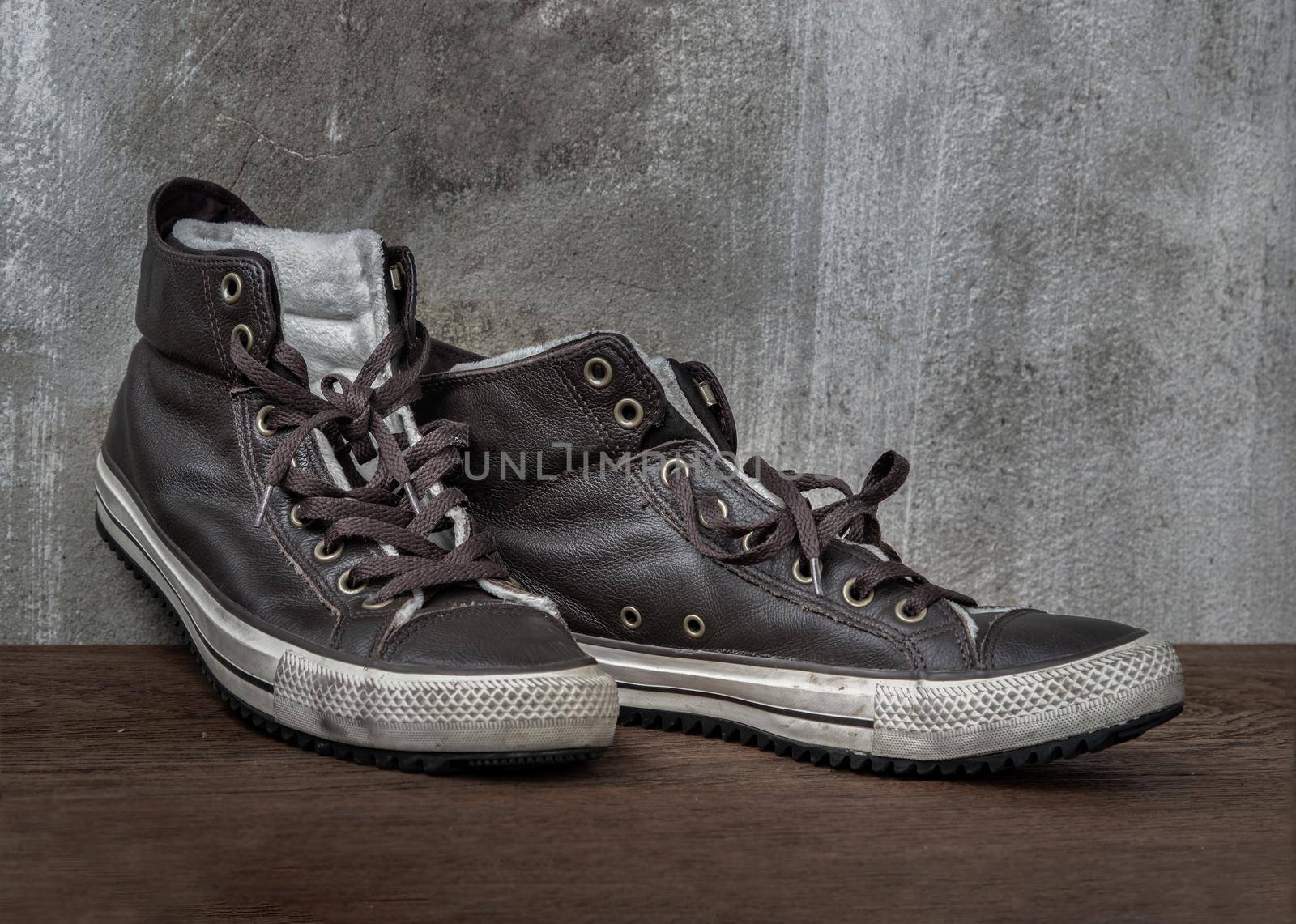 Brown Retro High Top Canvas Sneakers was placed on old wooden floor. Vintage age-worn sneakers canvas shoes brown, Concept : Sometimes the long journey of life should rest. Copy space, Selective focus.