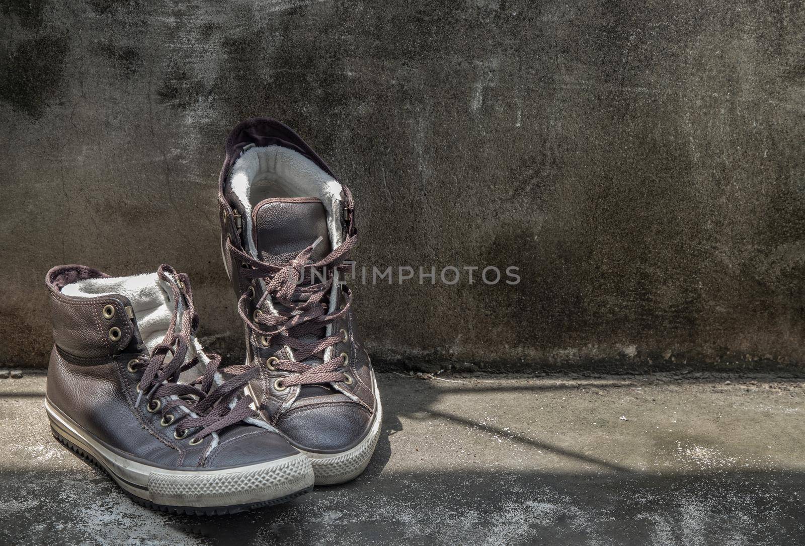 Brown Retro High Top Canvas Sneakers was placed on old cement floor. Vintage age-worn sneakers canvas shoes brown, Concept : Sometimes the long journey of life should rest. Copy space, Selective focus.
