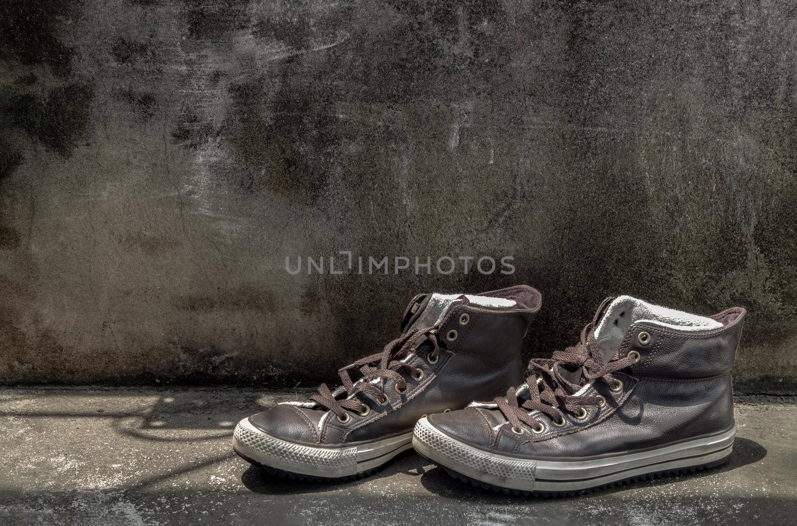 Brown Retro High Top Canvas Sneakers was placed on old cement floor. Vintage age-worn sneakers canvas shoes brown, Concept : Sometimes the long journey of life should rest. Copy space, Selective focus.