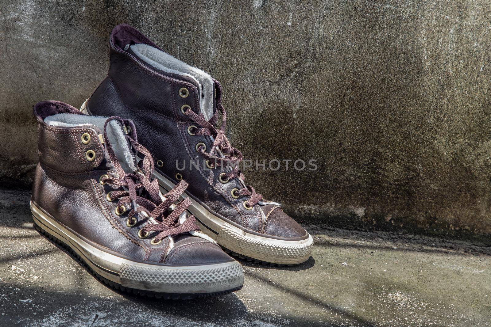 Brown Retro High Top Canvas Sneakers was placed on old cement floor. Vintage age-worn sneakers canvas shoes brown, Concept : Sometimes the long journey of life should rest. Copy space, Selective focus.
