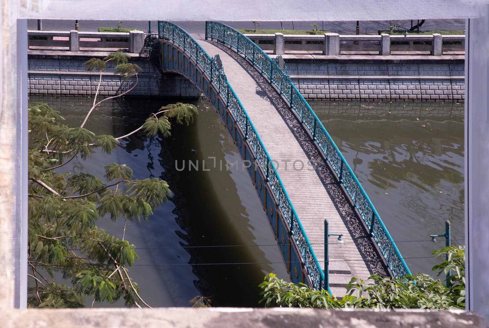 The bridge over the small canal looks through the window frames in abandoned building. Selective focus