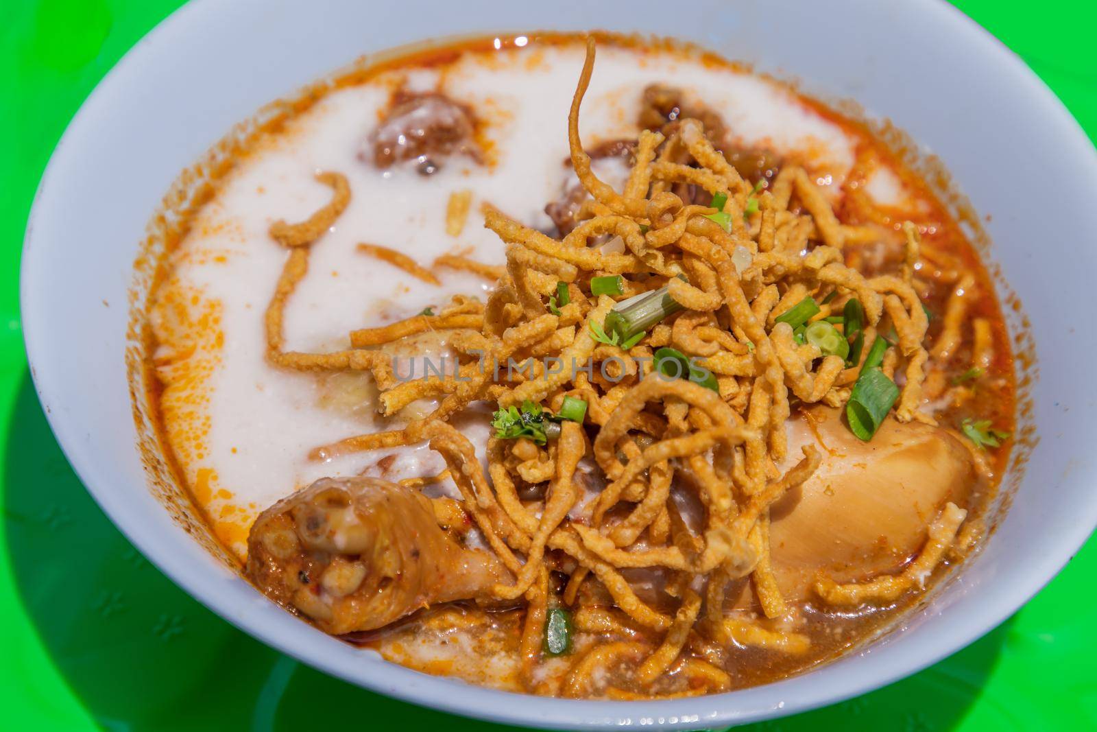 Traditional Khao Soi Recipe, Thai Northern Style Curried Noodle Soup with Chicken in white bowl. Selective focus.