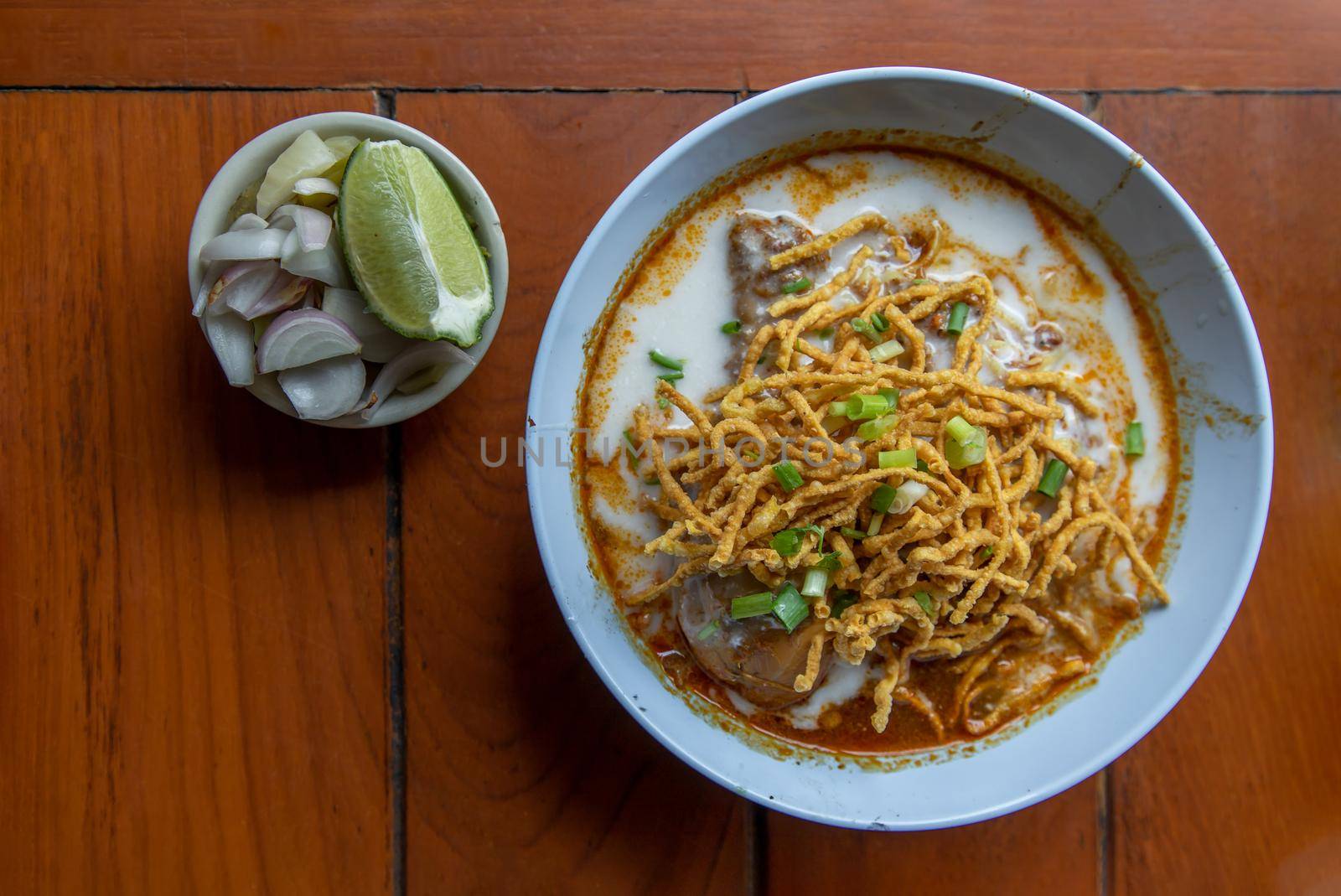 Traditional Khao Soi Recipe, Thai Northern Style Curried Noodle Soup with Chicken in white bowl. Selective focus.