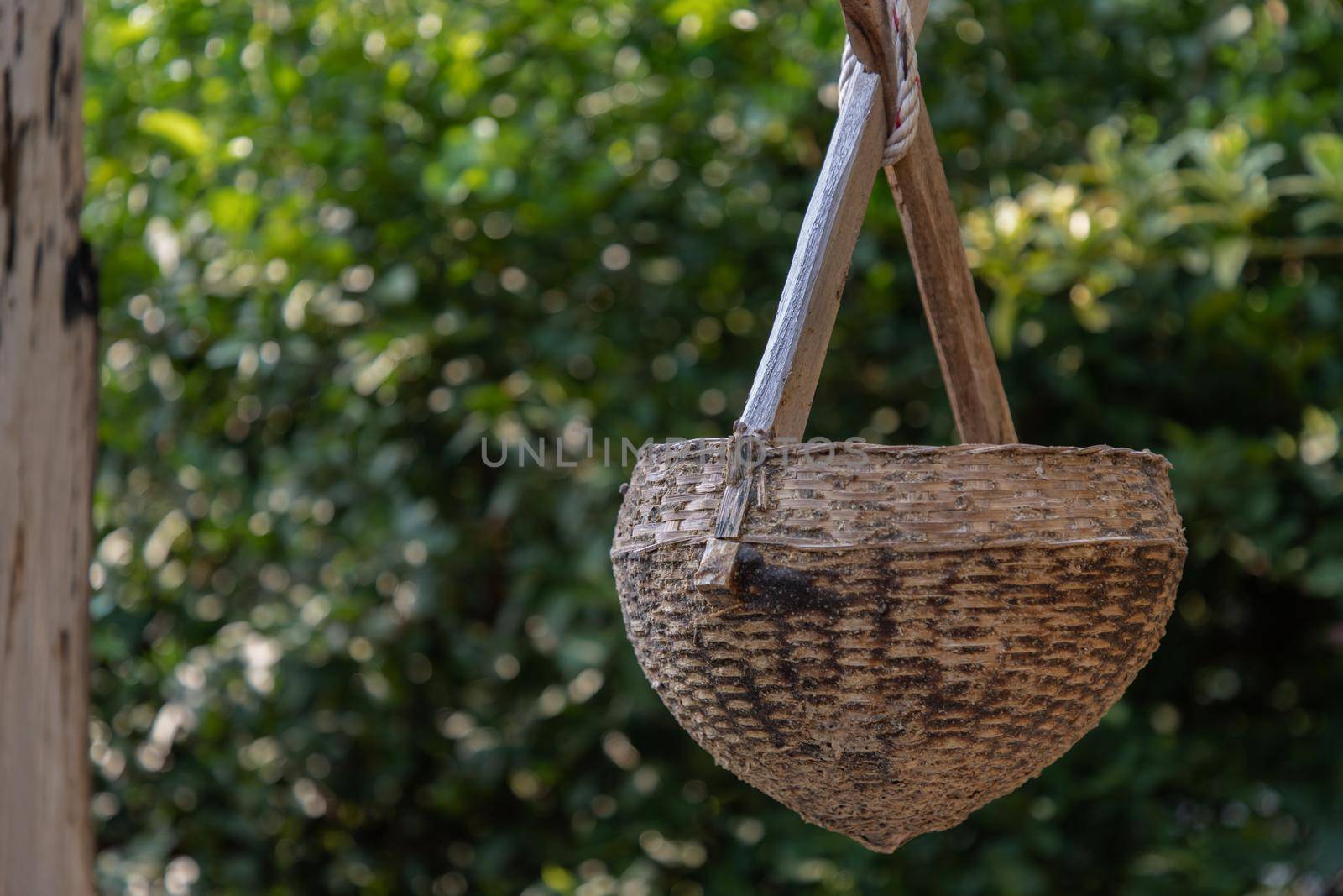 Ancient wooden water scoop for scooping water. At time of scooping the rope, put wooden water scoop into the pond to draw water. Selective focus.