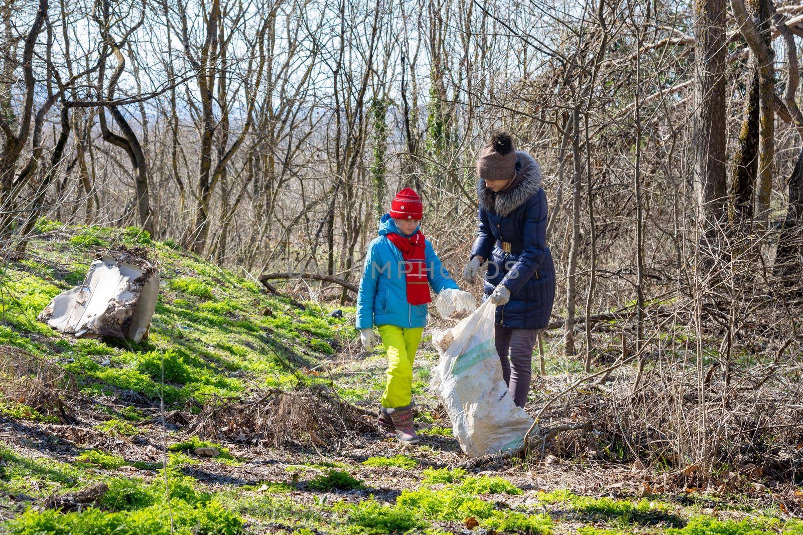 Family collects trash in the forest in a big bag for recycling