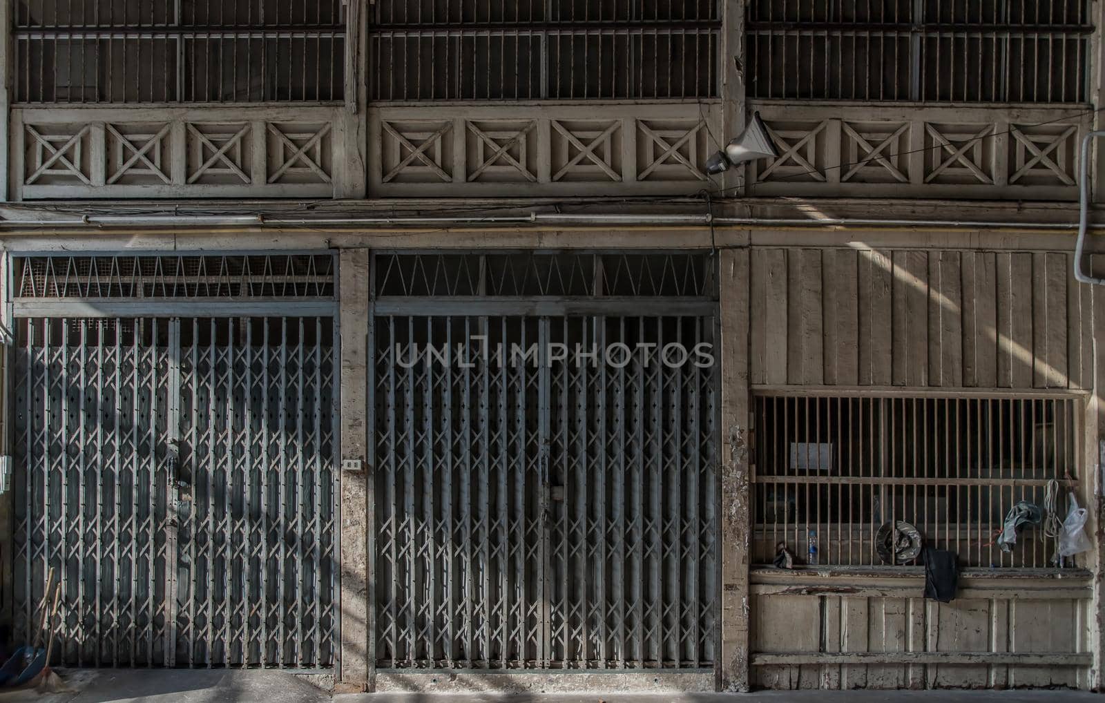 Front view of entrance of the building and old steel metal shutter and folding door gate on old industrl building. No focus, specifically.