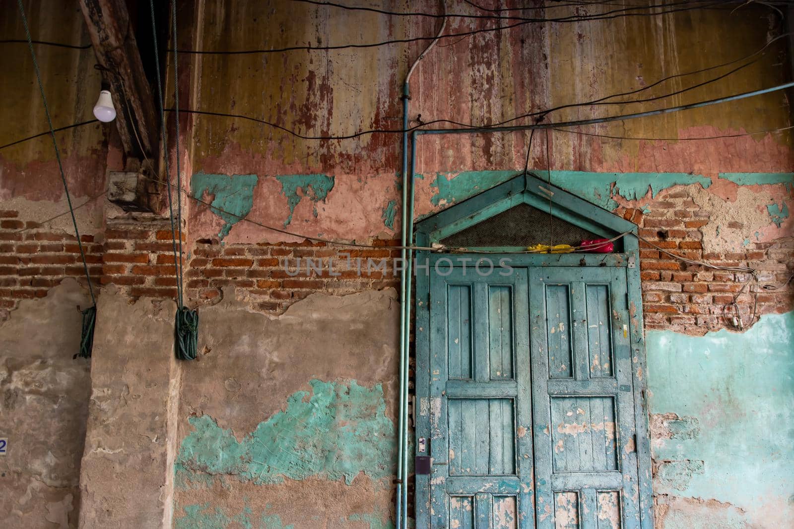 Old wood vintage door on the old wall with visible bricks texture was left to deteriorate over time. Traditional Architecture style, Selective focus.