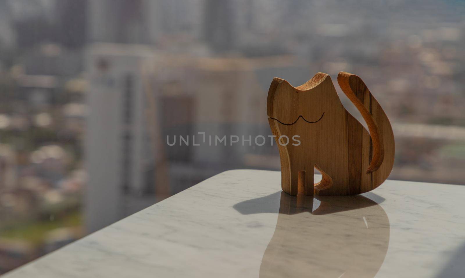 Wooden doll in cat shape on marble table in the morning. Copy space, Selective focus.