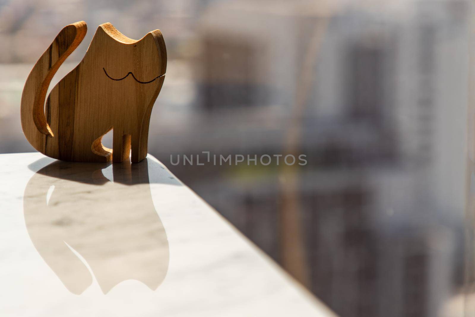 Wooden doll in cat shape on marble table in the morning. Copy space, Selective focus.
