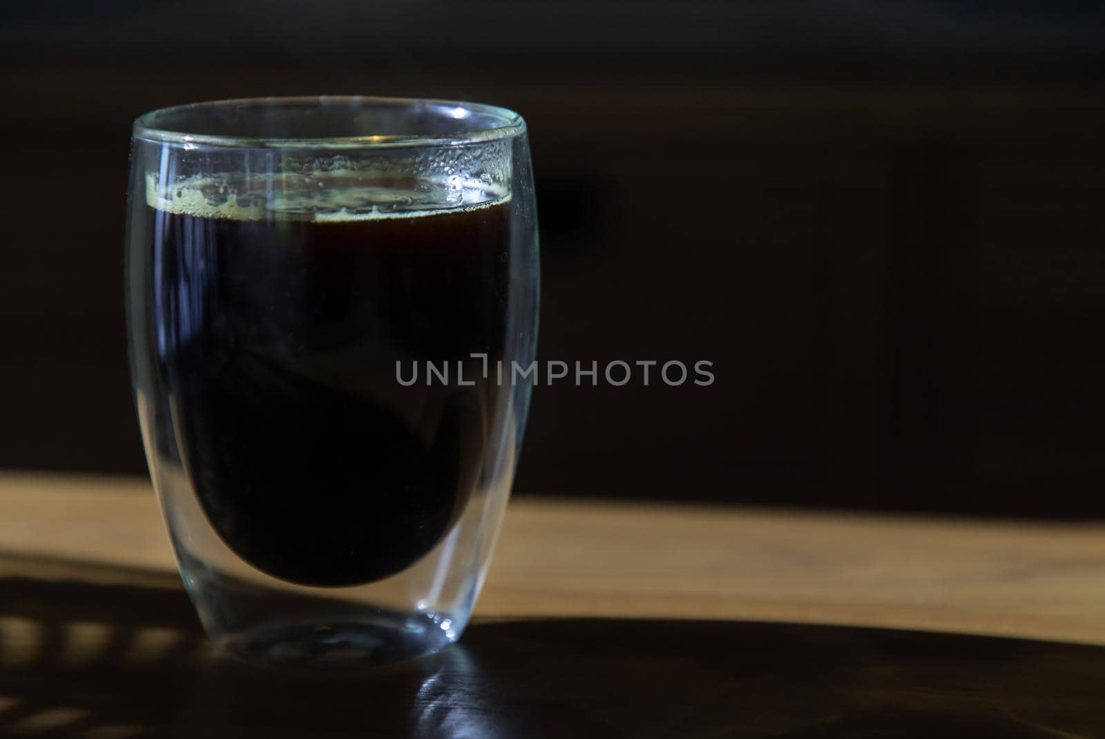Black coffee in glass cup on wooden table in the room. Coffee style, Copy space, Selective focus.