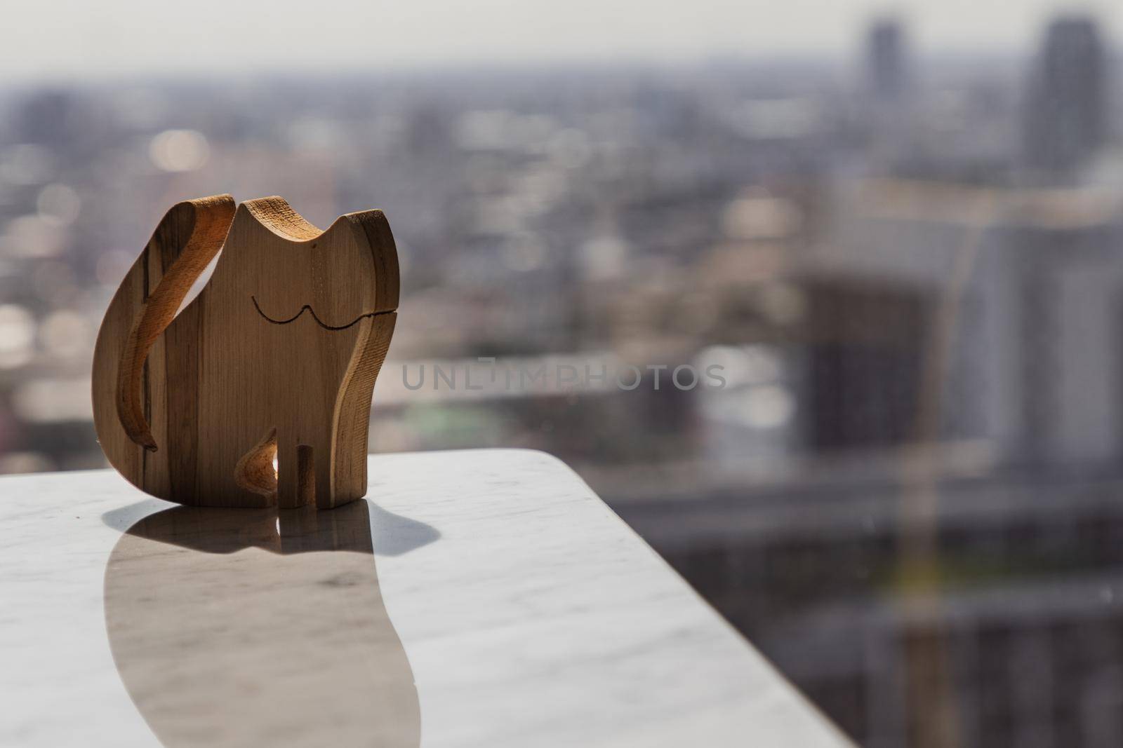 Wooden doll in cat shape on marble table in the morning. Copy space, Selective focus.
