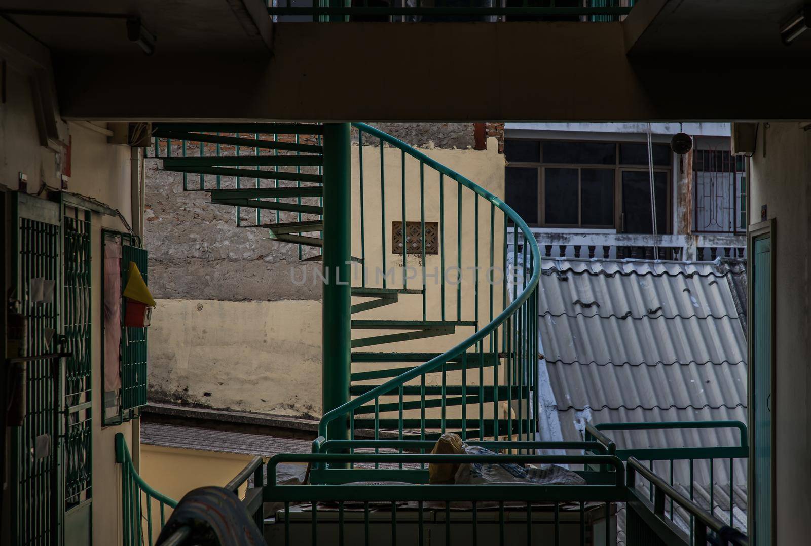 Bangkok, Thailand - 25 Jan 2020 : Green spiral staircase pattern in old apartment. Spiral stairs circle in courtyard architecture. Outdoor ladder decoration interior. Selective focus.