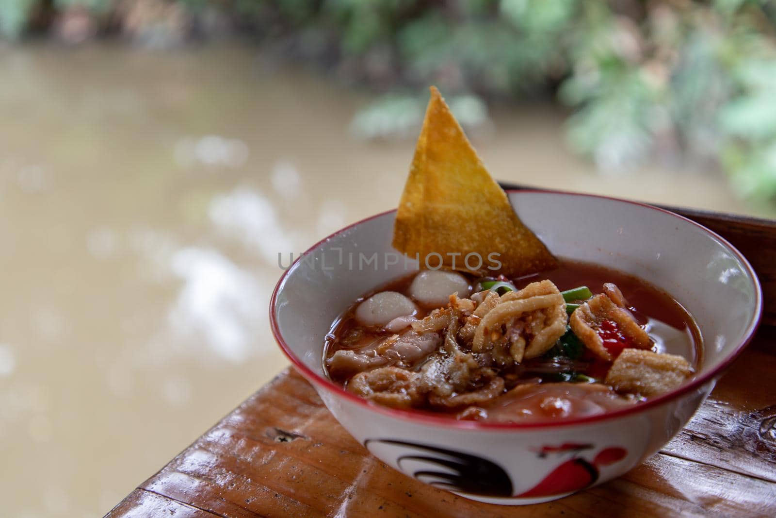 Yentafo Thai Noodle with pink soup in ceramic bowl on wooden table. Copy space, Selective focus.