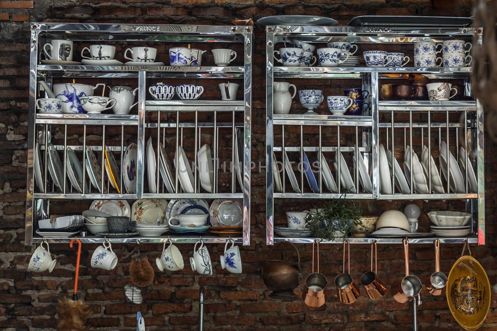 Luxury ceramic tableware on stainless shelves on the red brick wall. No focus, specifically.