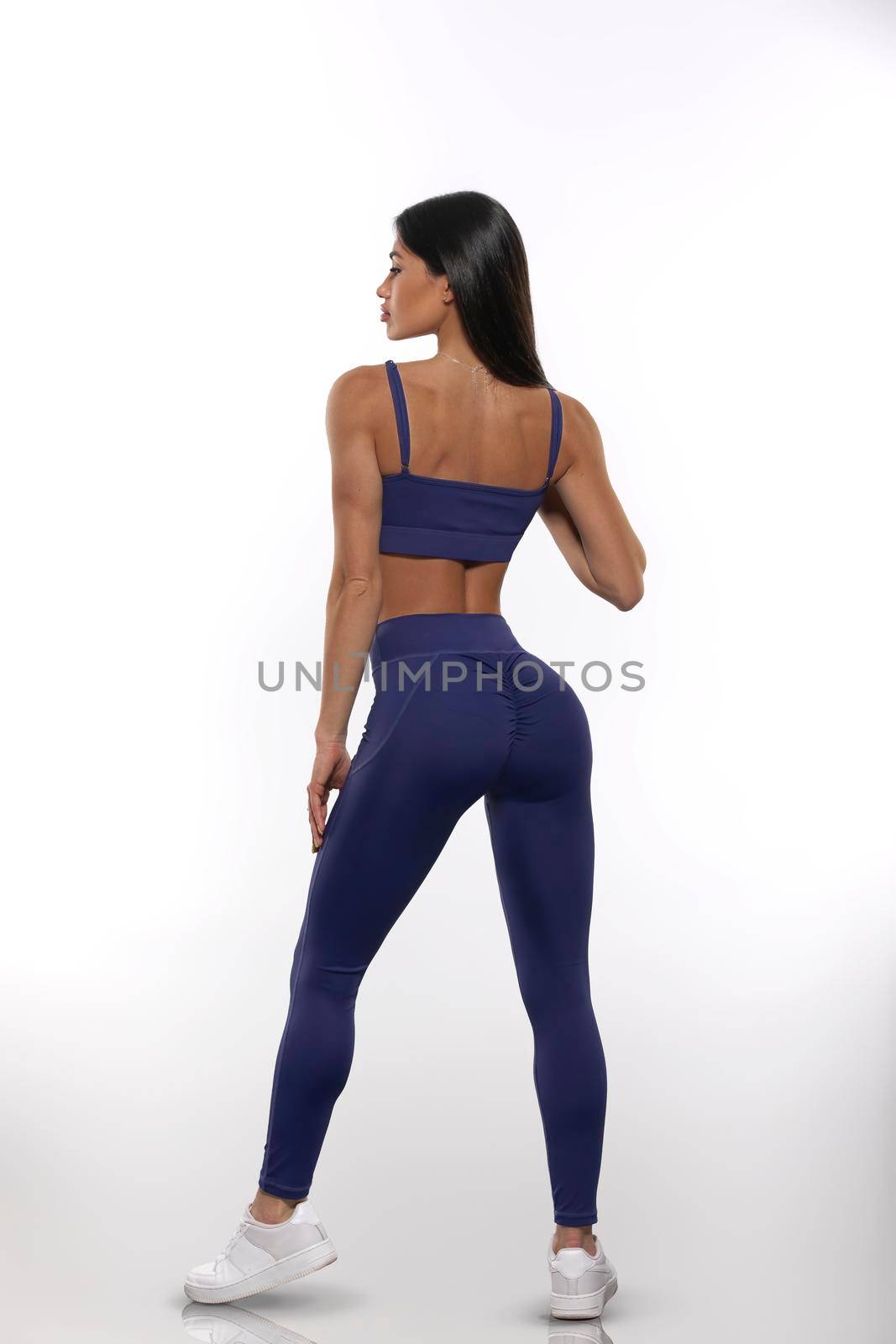brunette girl in blue leggings and top stay back on a white background