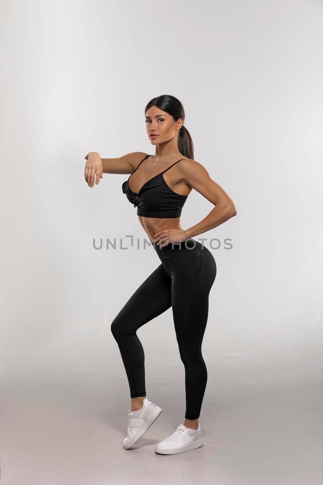 brunette girl in black leggings and a top on a white background