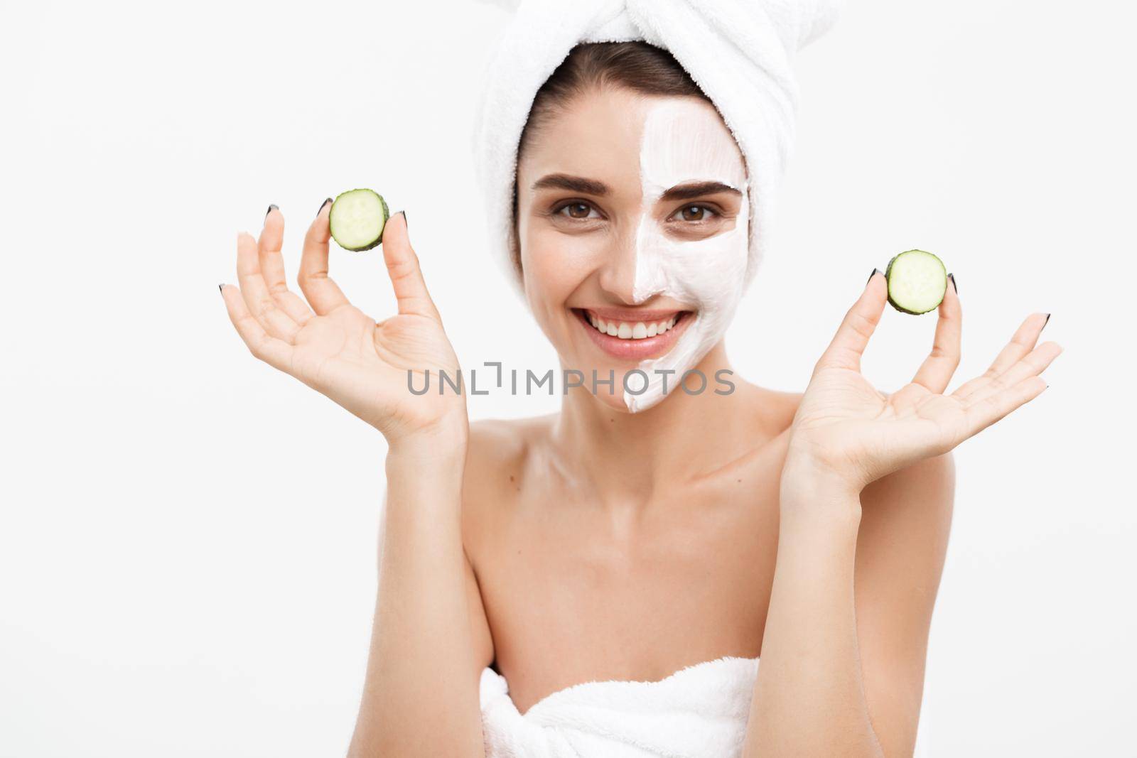 Beauty Youth Skin Care Concept - Portrait Beautiful Caucasian Woman apply cream and holding fresh cucumber in front of her face.Isolated over white background