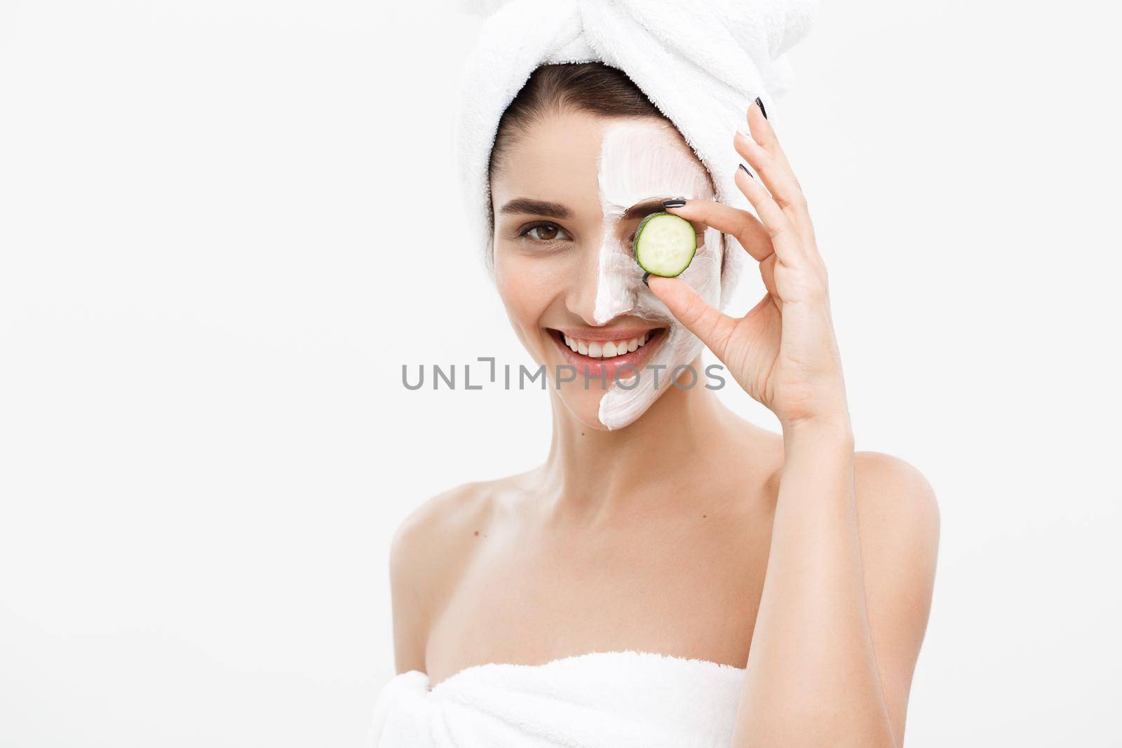 Beauty Youth Skin Care Concept - Portrait Beautiful Caucasian Woman apply cream and holding fresh cucumber in front of her face.Isolated over white background. by Benzoix