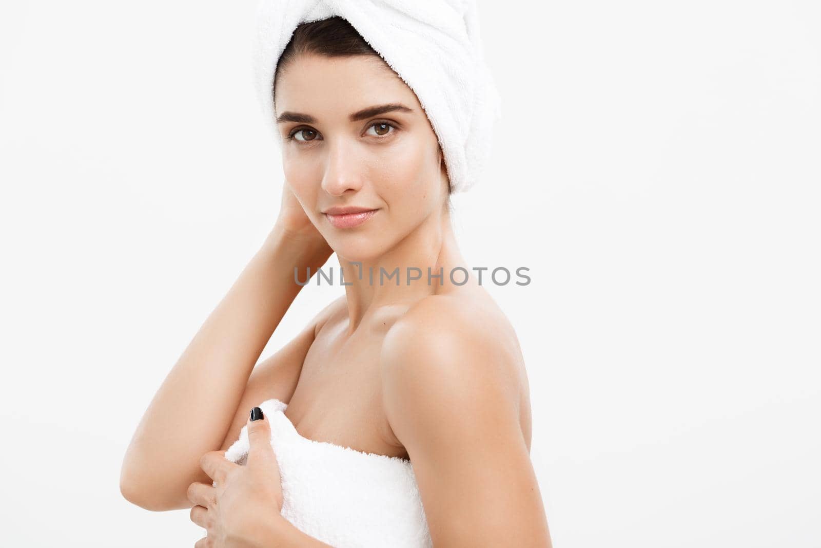 Beauty and Skin care concept - Beautiful caucasian Young Woman with bath towel on head covering her breasts, on white