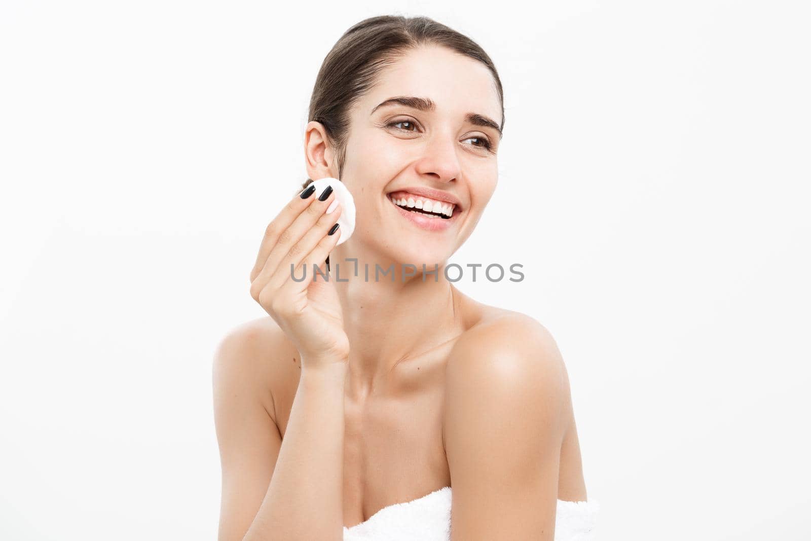 Beauty Skin Care Concept - Beautiful woman cleaning her face with cotton swab - over white background and smiling