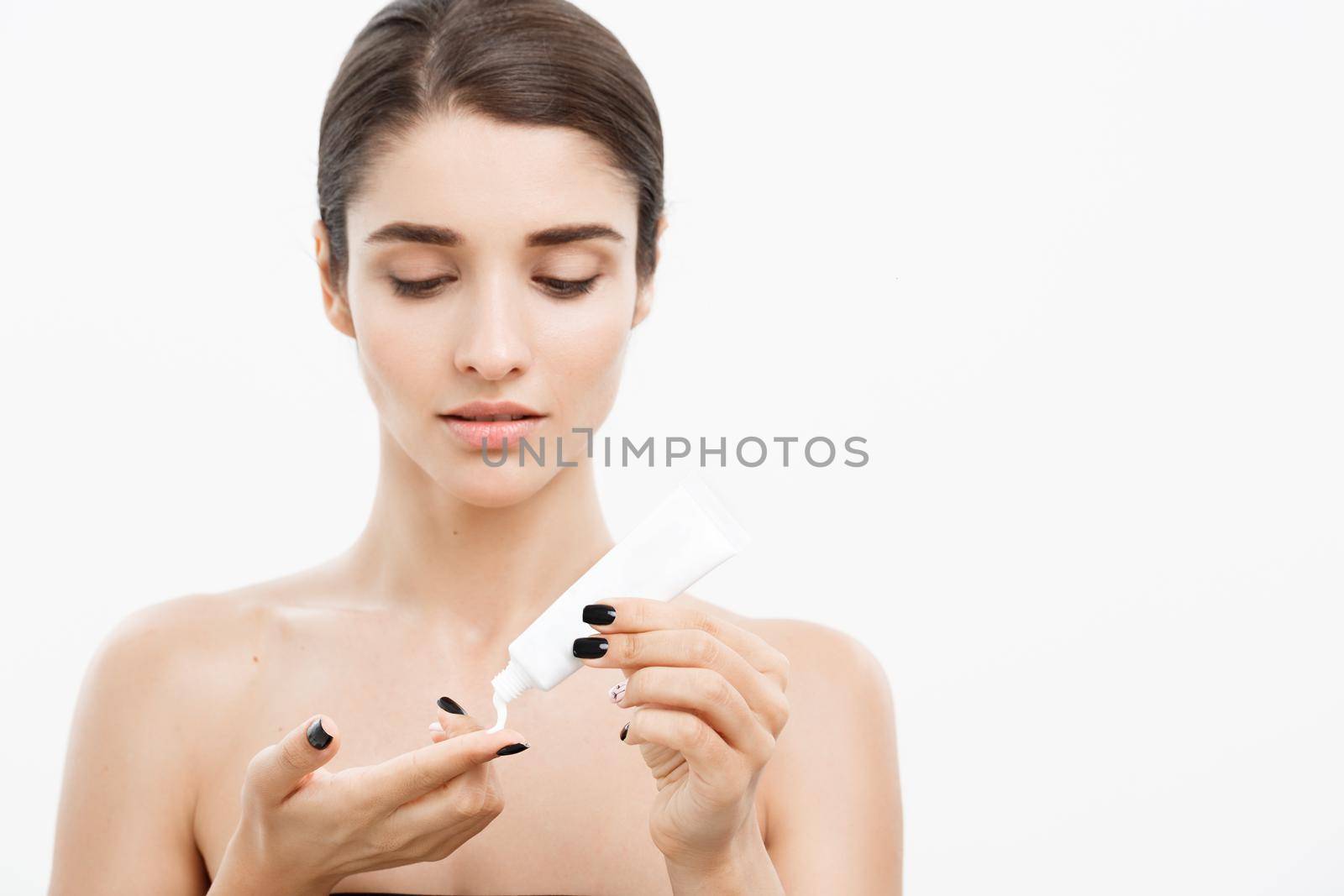 Beauty Youth Skin Care Concept - Close up Beautiful Caucasian Woman Face Portrait holding cream tube with nourishing cream for applying to skin Isolated on white background. by Benzoix