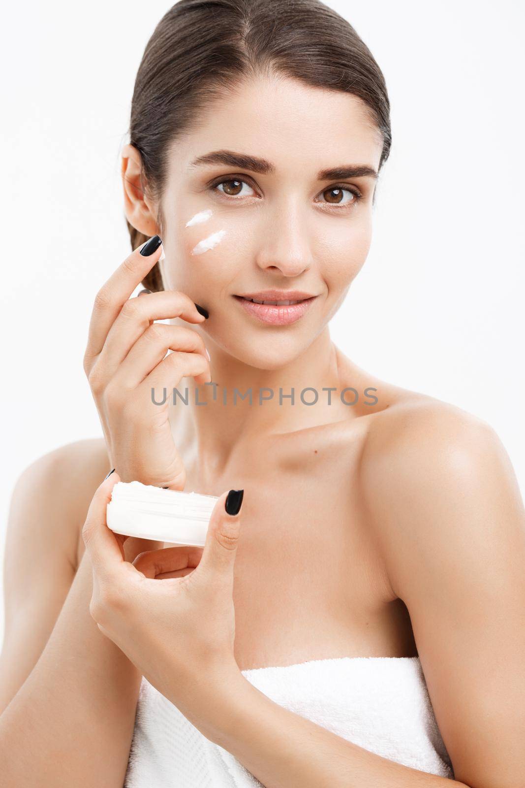 Beauty Youth Skin Care Concept - Close up Beautiful Caucasian Woman Face Portrait applying some cream to her face. Beautiful Spa model Girl with Perfect Fresh Clean Skin over white background