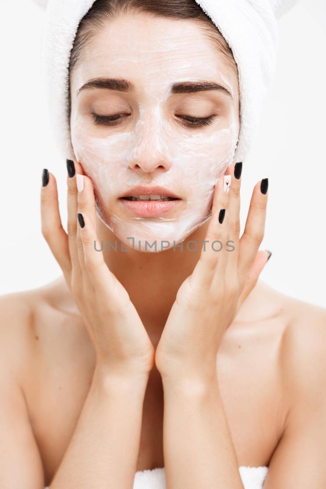 Beauty Skin Care Concept - Beautiful Caucasian Woman Face Portrait applying cream mask on her facial skin white background. by Benzoix