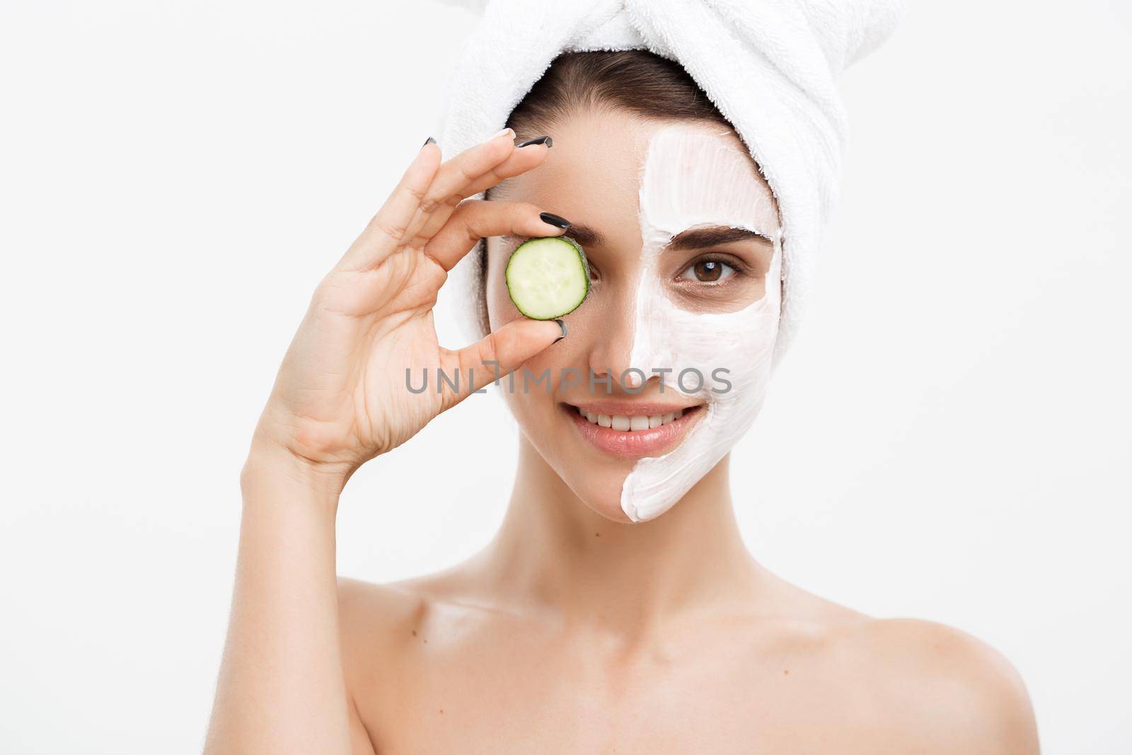 Beauty Youth Skin Care Concept - Portrait Beautiful Caucasian Woman apply cream and holding fresh cucumber in front of her face.Isolated over white background