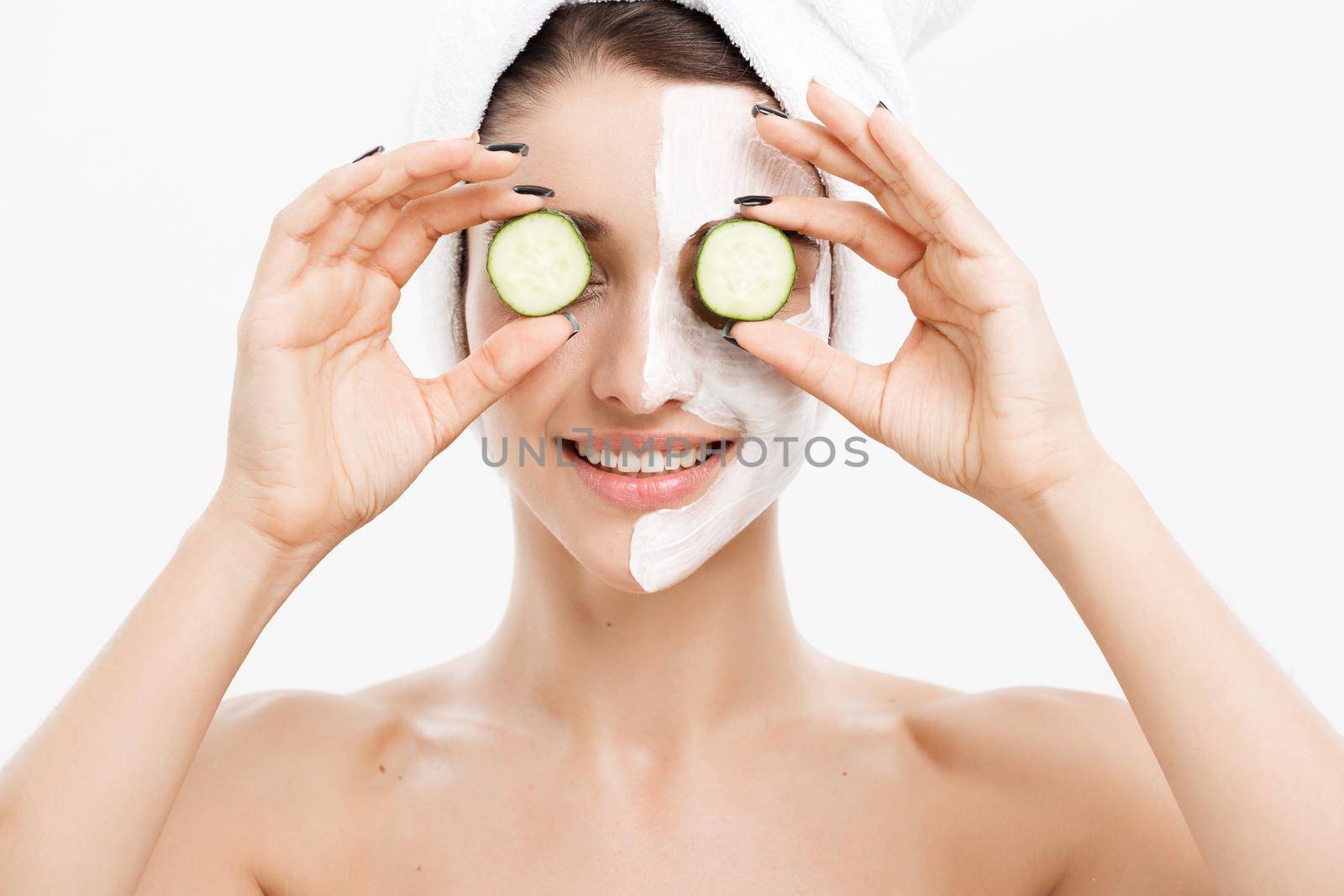 Beauty Youth Skin Care Concept - Portrait Beautiful Caucasian Woman apply cream and holding fresh cucumber in front of her face.Isolated over white background. by Benzoix