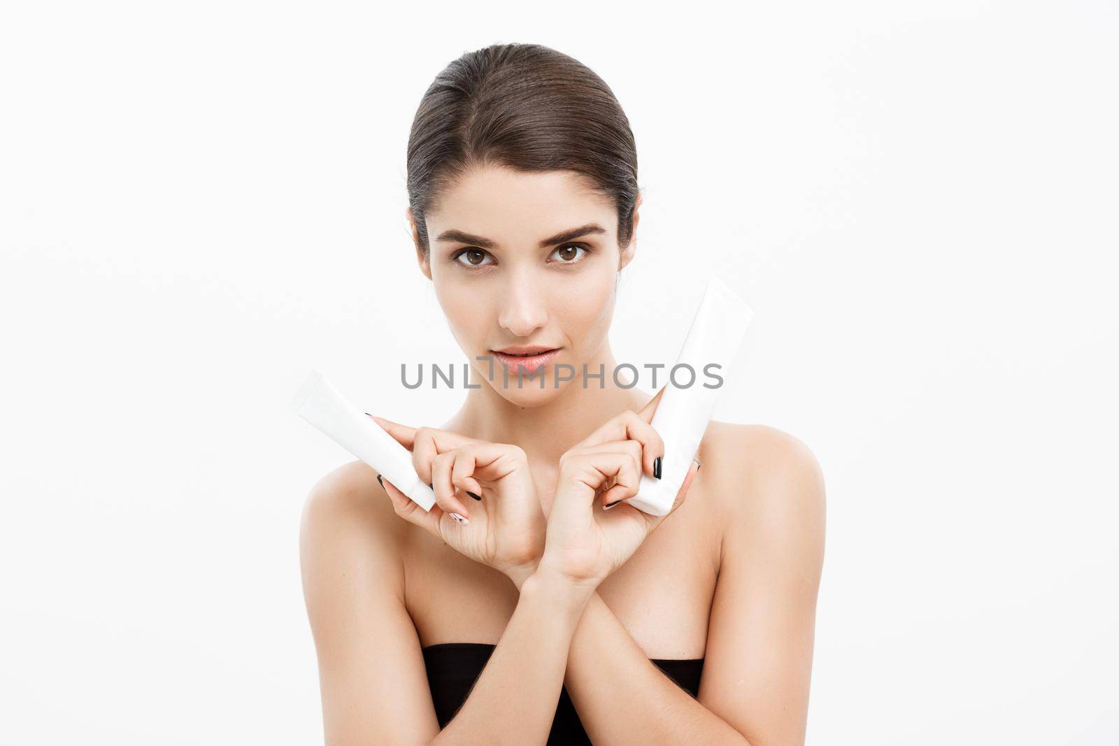 Beauty Youth Skin Care Concept - Beautiful Caucasian Woman Face Portrait holding and presenting cream tube product. Beautiful Spa model Girl with Perfect Fresh Clean Skin over white background. by Benzoix