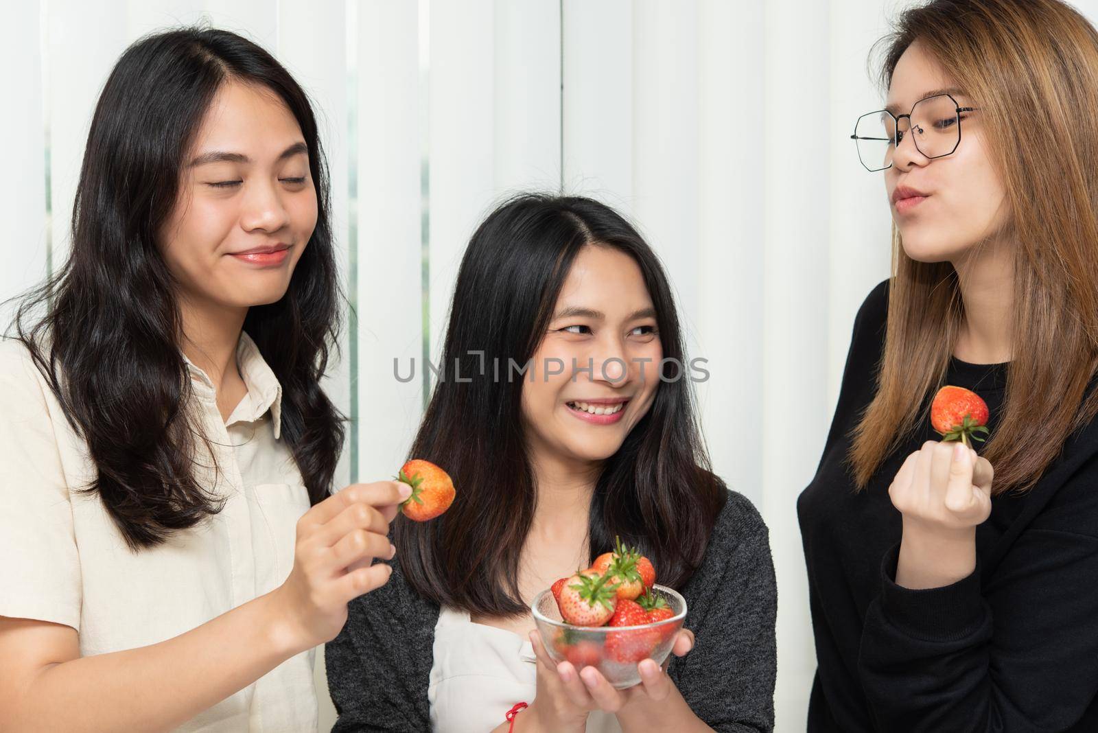 Asian pretty women holding and eating fresh strawberry is red berry fruit color and sweet juicy with enjoy and happy emotion in concept food, healthy eating in life
