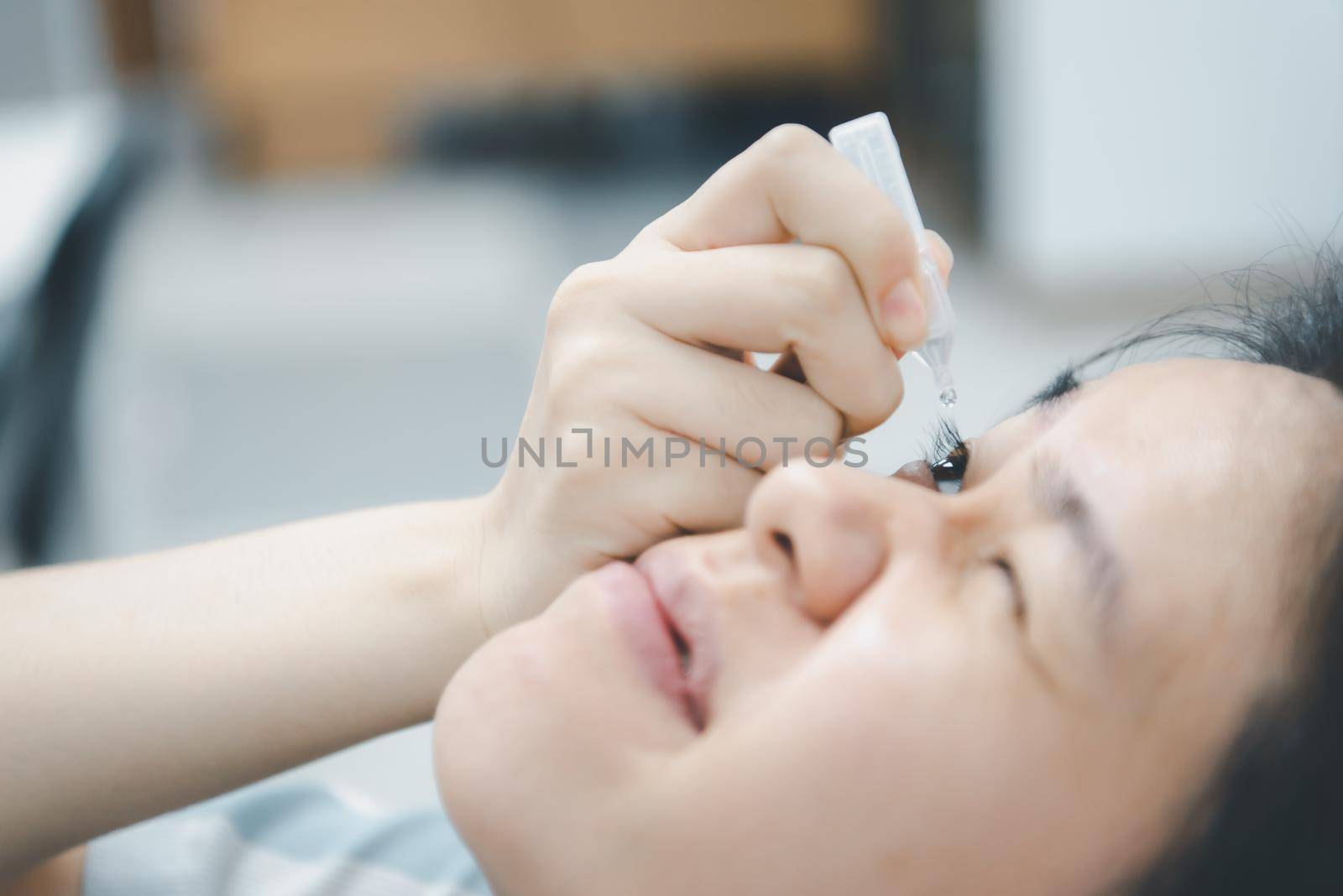 Woman use eye drop, artificial tears to the eye by PongMoji