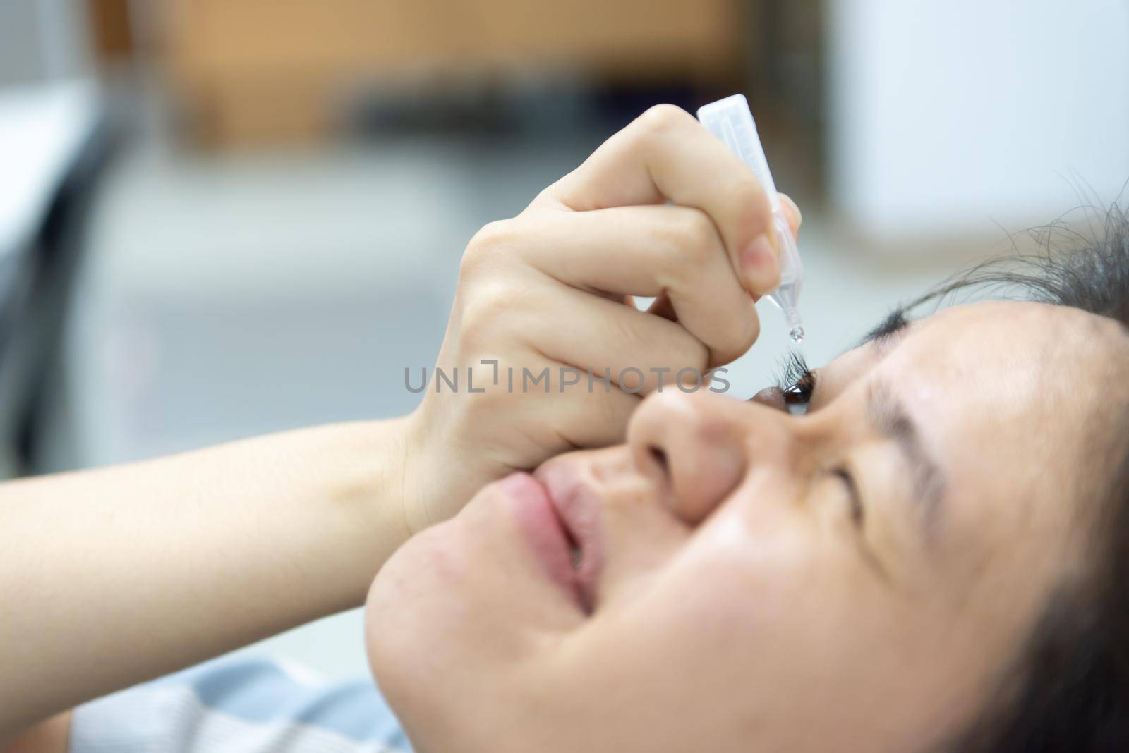 Woman use eye drop, artificial tears to the eye by PongMoji