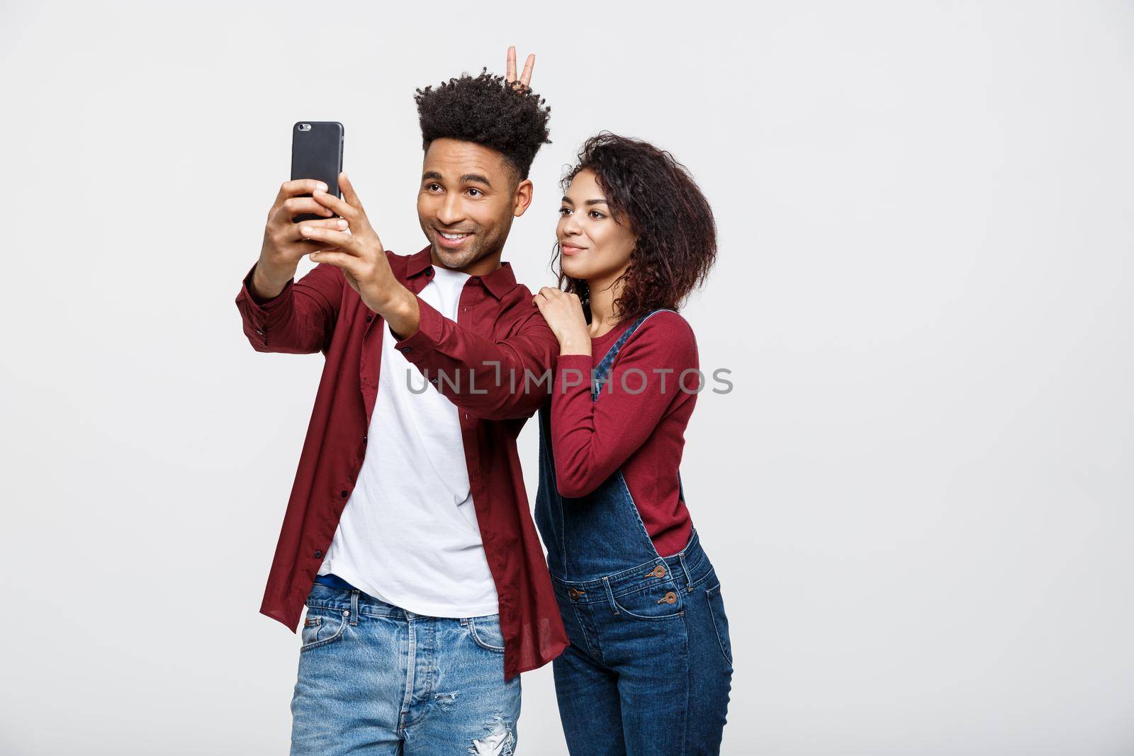 Young attractive African American Couple Pose For selfie pose with smart phone.