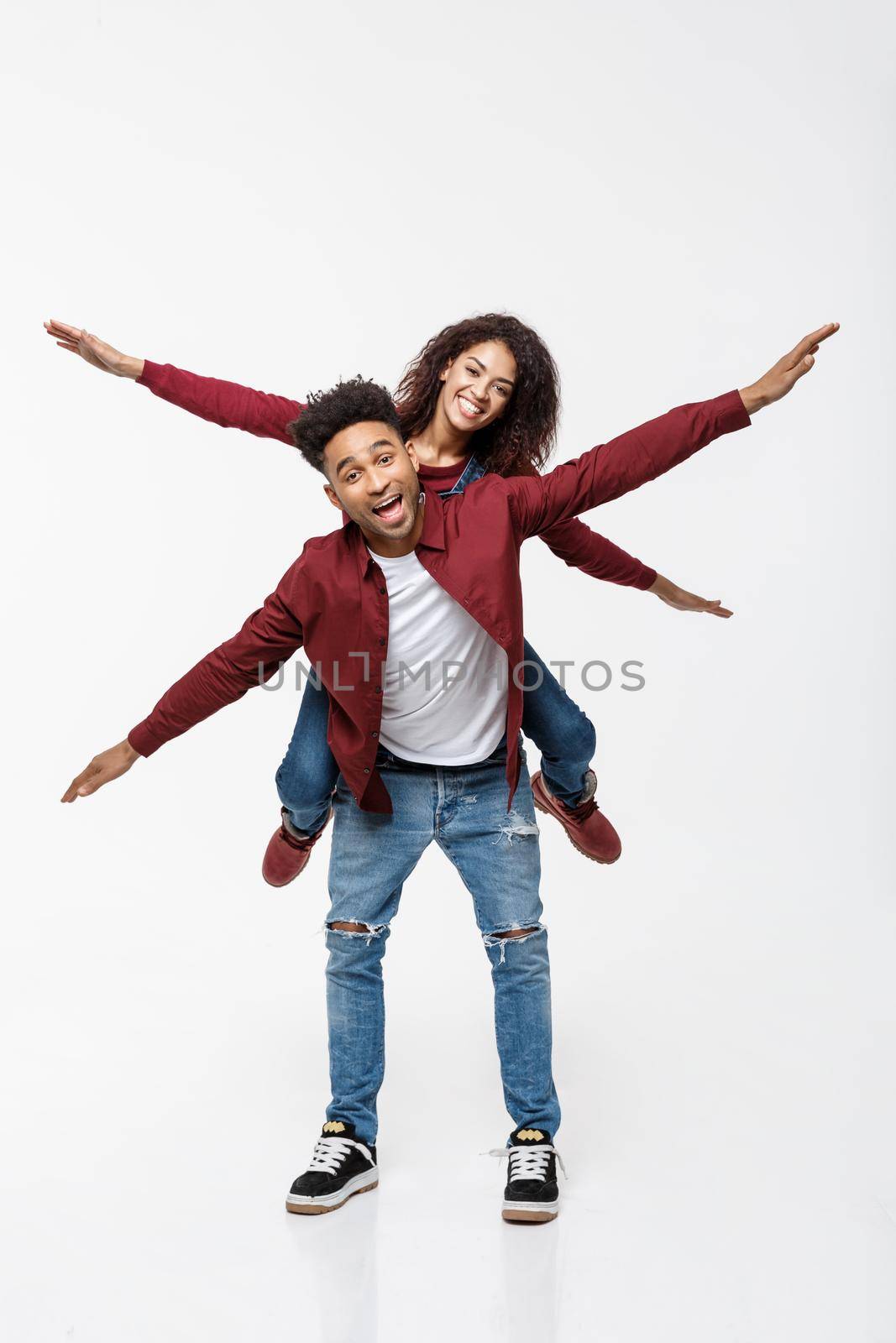 Full length young attractive african american lady riding back on her boyfriend back and enjoy playing to each other. by Benzoix