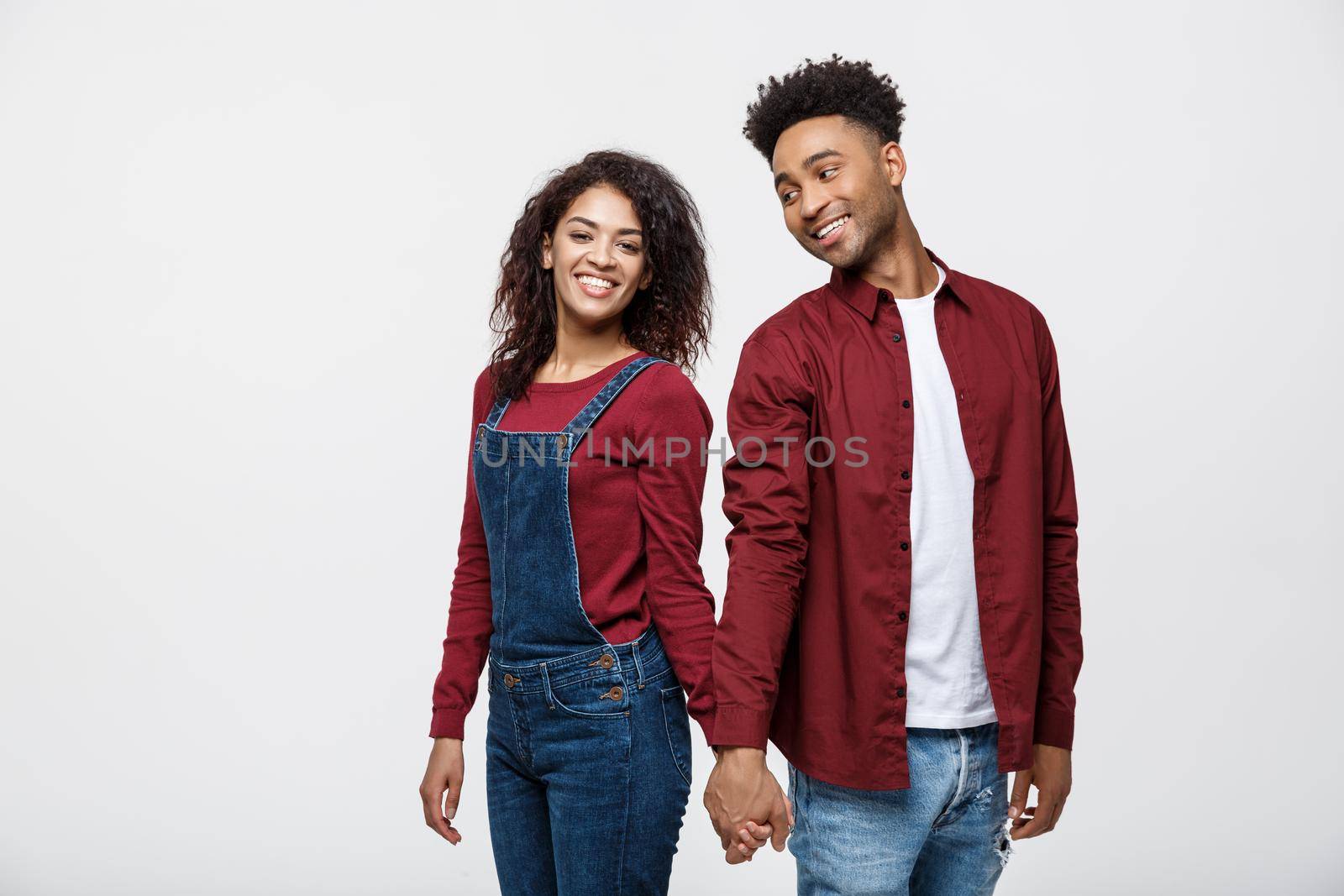 happy african american couple holding hands and looking back isolated on white by Benzoix