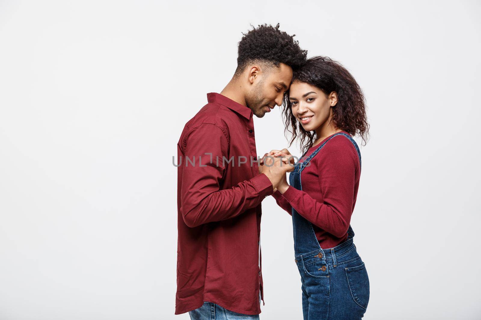 Side view of beautiful African American young couple in classic shirts holding hands, looking at each other and smiling