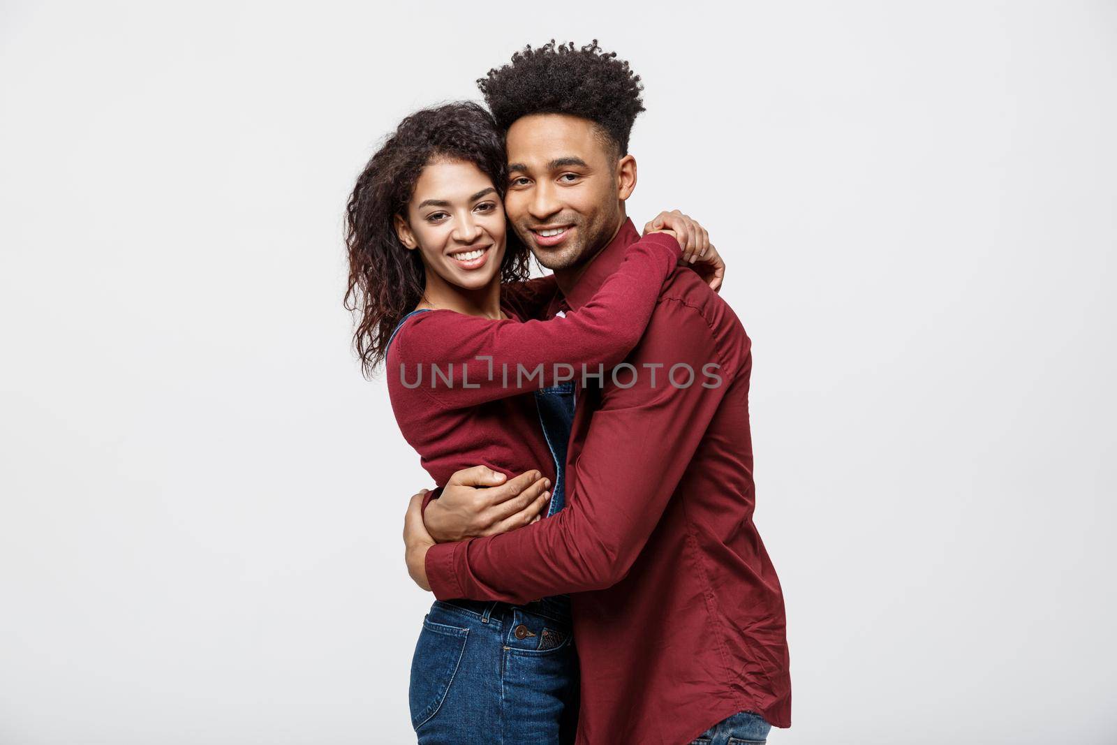 Portrait beautiful young African couple standing close to each other and smiling at camera while isolated on white.