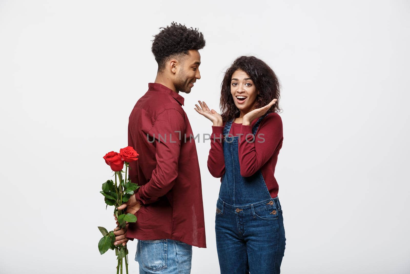 Beautiful elegant couple is hugging and smiling, on gray background. Girl is holding roses by Benzoix